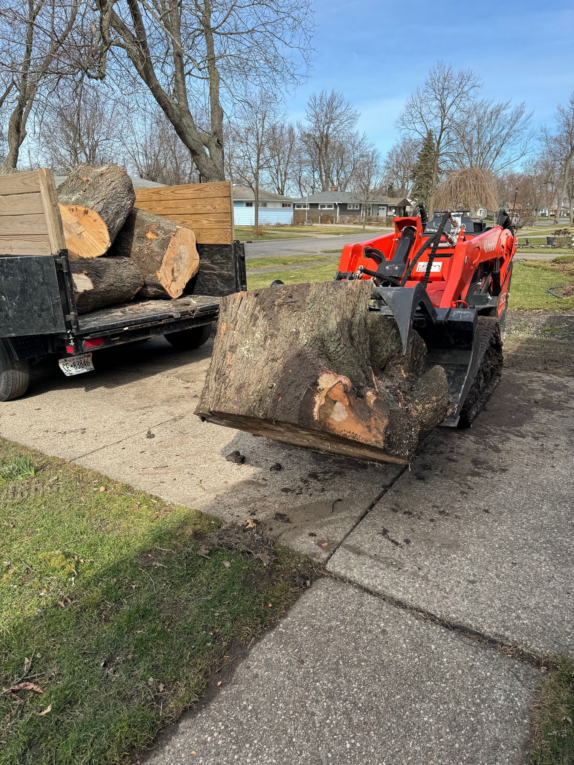 A stump grinder is being used to remove a tree stump from a sidewalk.