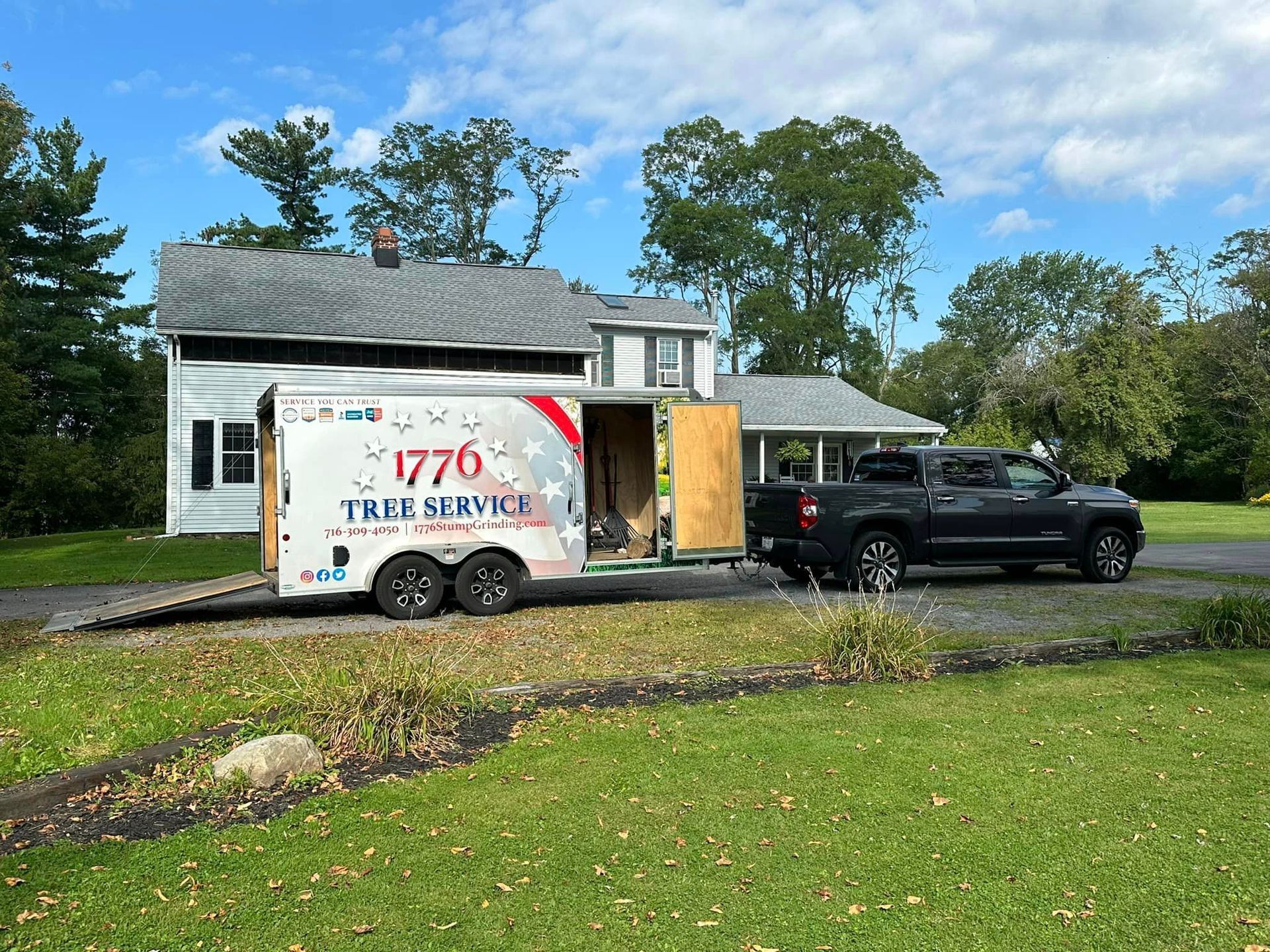 A truck and trailer are parked in front of a house.