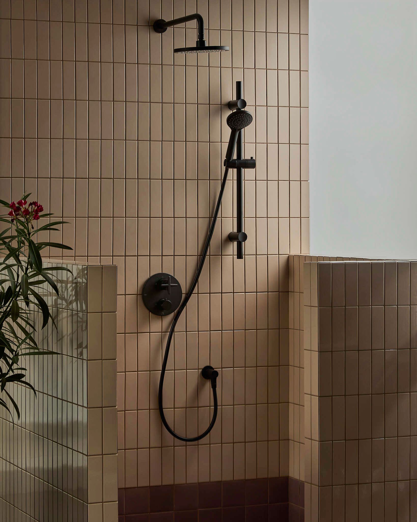 Pommeau de douche noir et douche à main dans une cabine de douche carrelée.