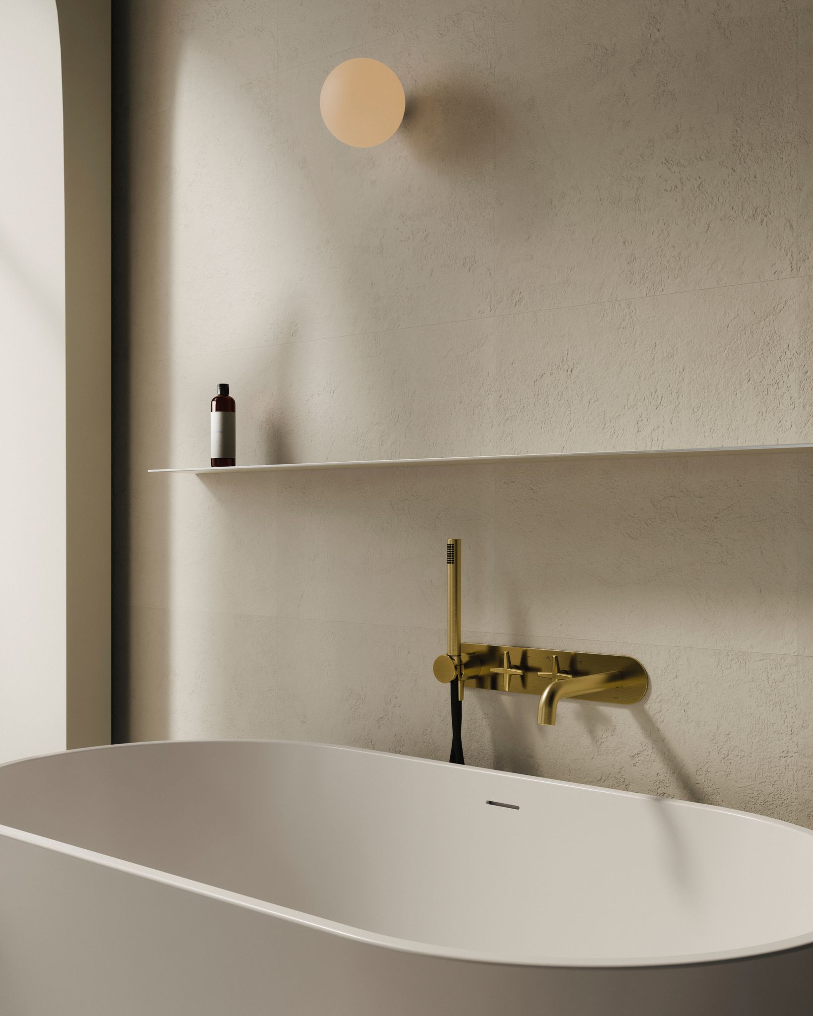 Salle de bain moderne avec une baignoire blanche, un robinet doré, une étagère avec une bouteille foncée et un luminaire rond.