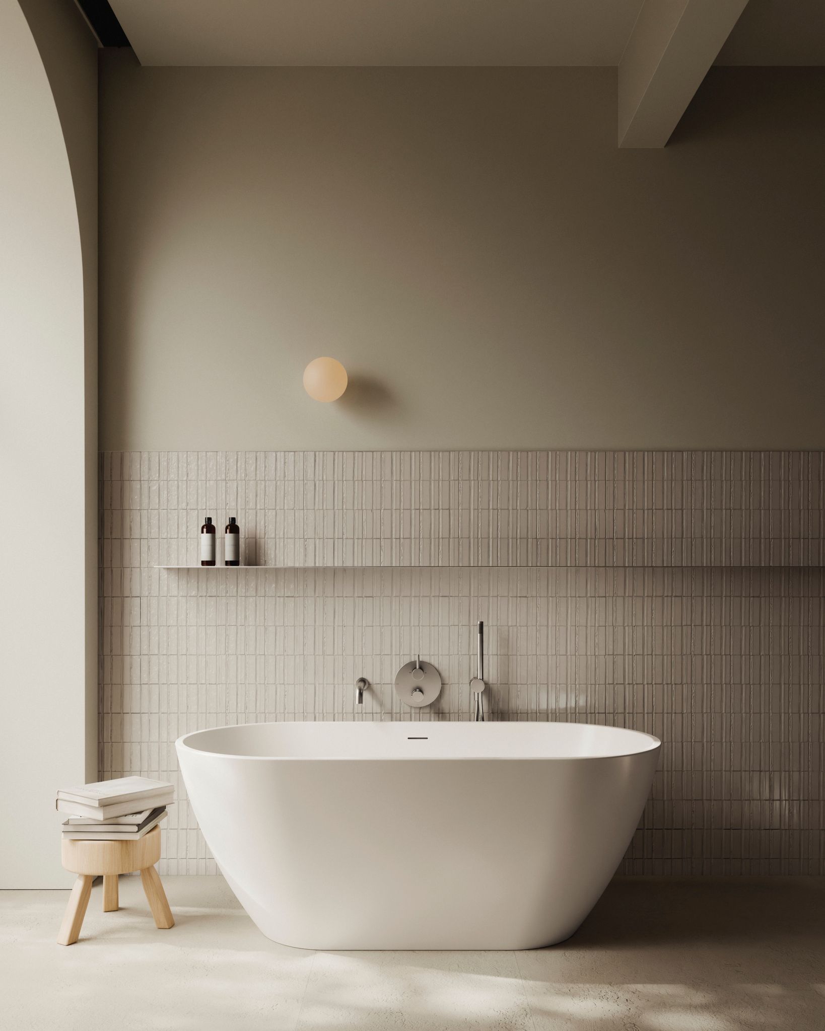 Salle de bain moderne avec baignoire blanche, mur carrelé, mur vert olive et tabouret avec livres.