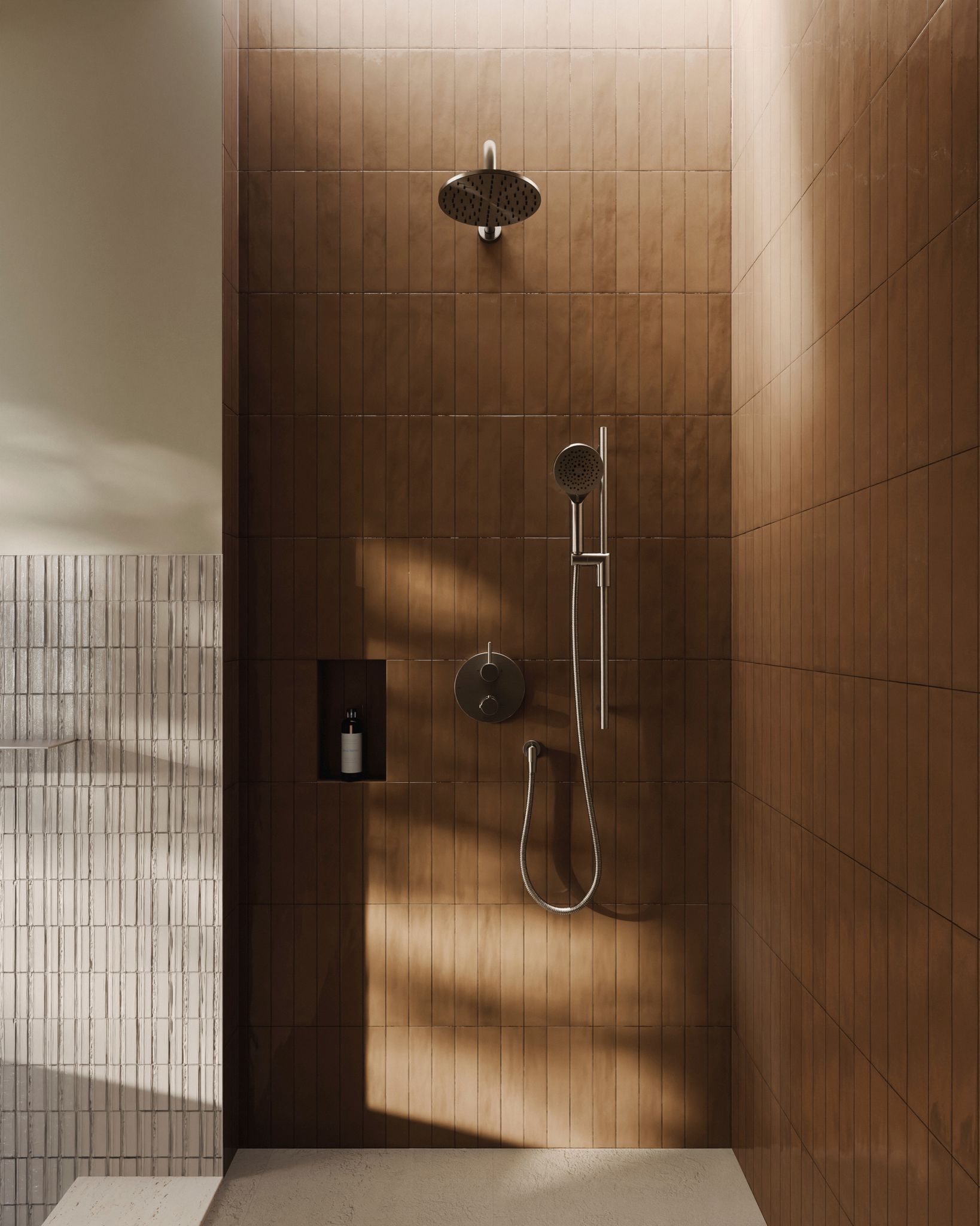 Douche avec murs carrelés marron, luminaires argentés, étagère encastrée avec bouteille et lumière sur le côté.