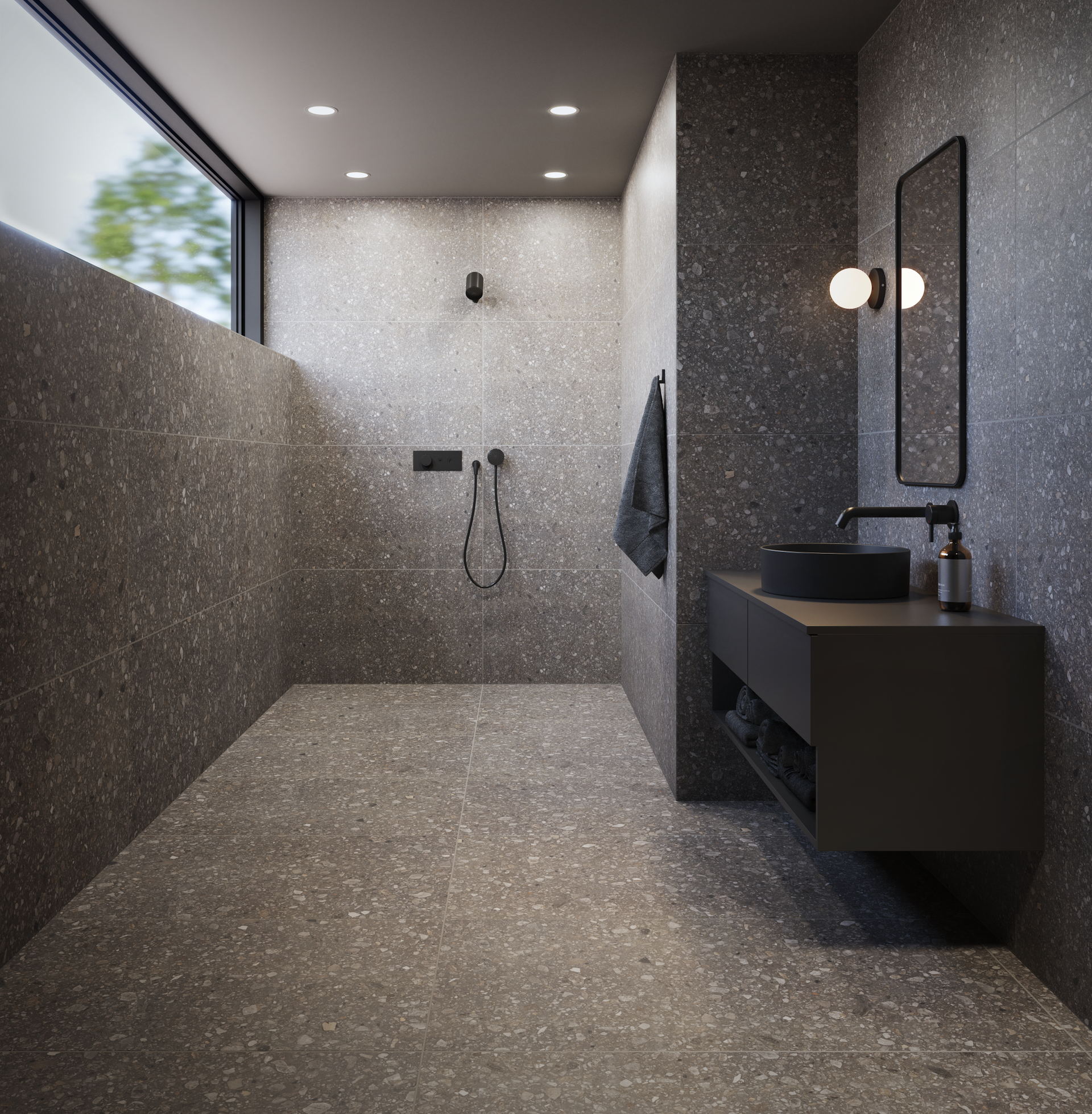 Salle de bain moderne avec carrelage en terrazzo, luminaires noirs, vanité sombre et vue sur la fenêtre.