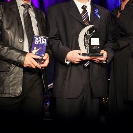 Trois personnes en tenue de soirée tenant des récompenses lors d'un gala.