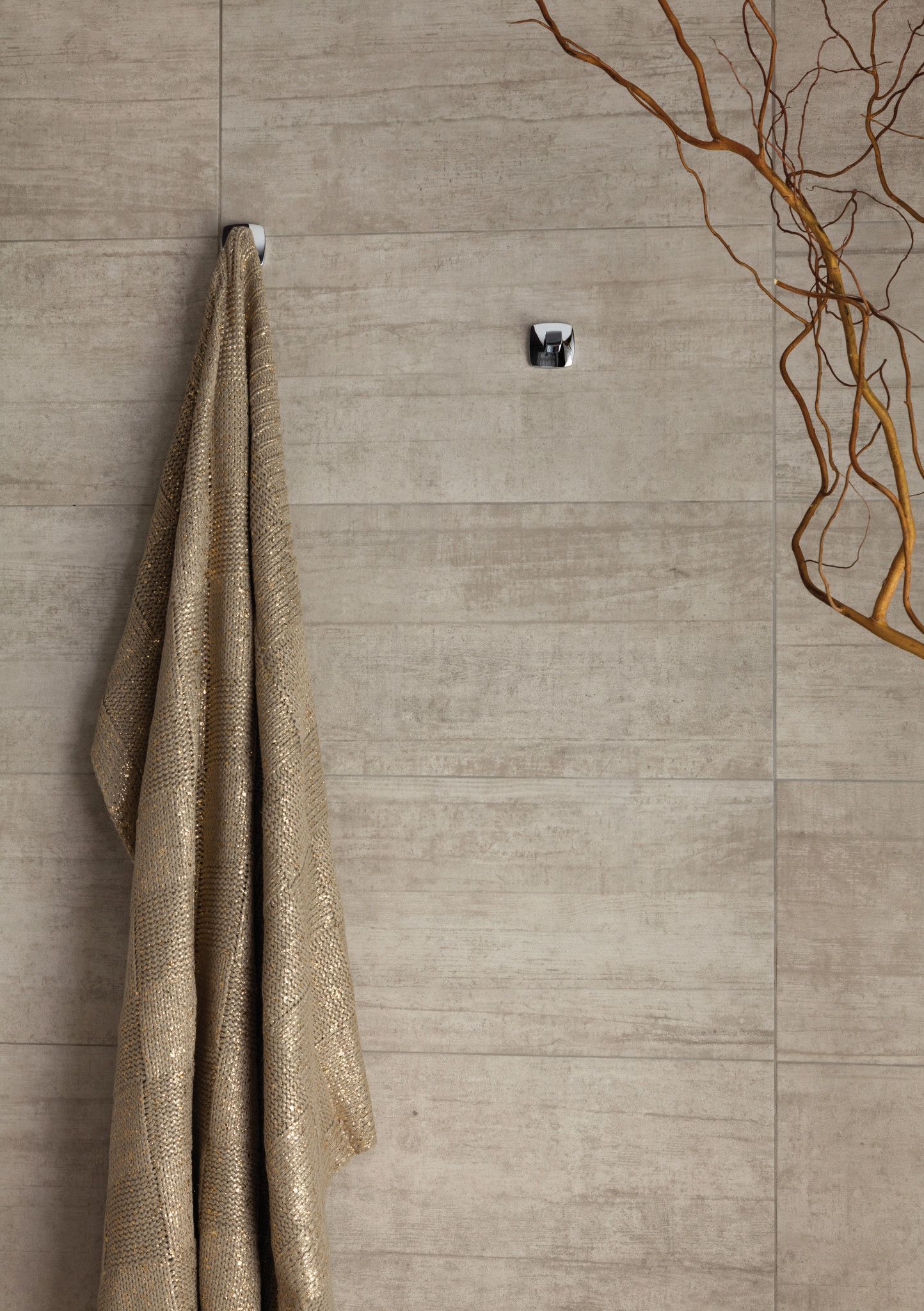 Serviette accrochée à un crochet mural. Serviette beige et mur décoré de branches.