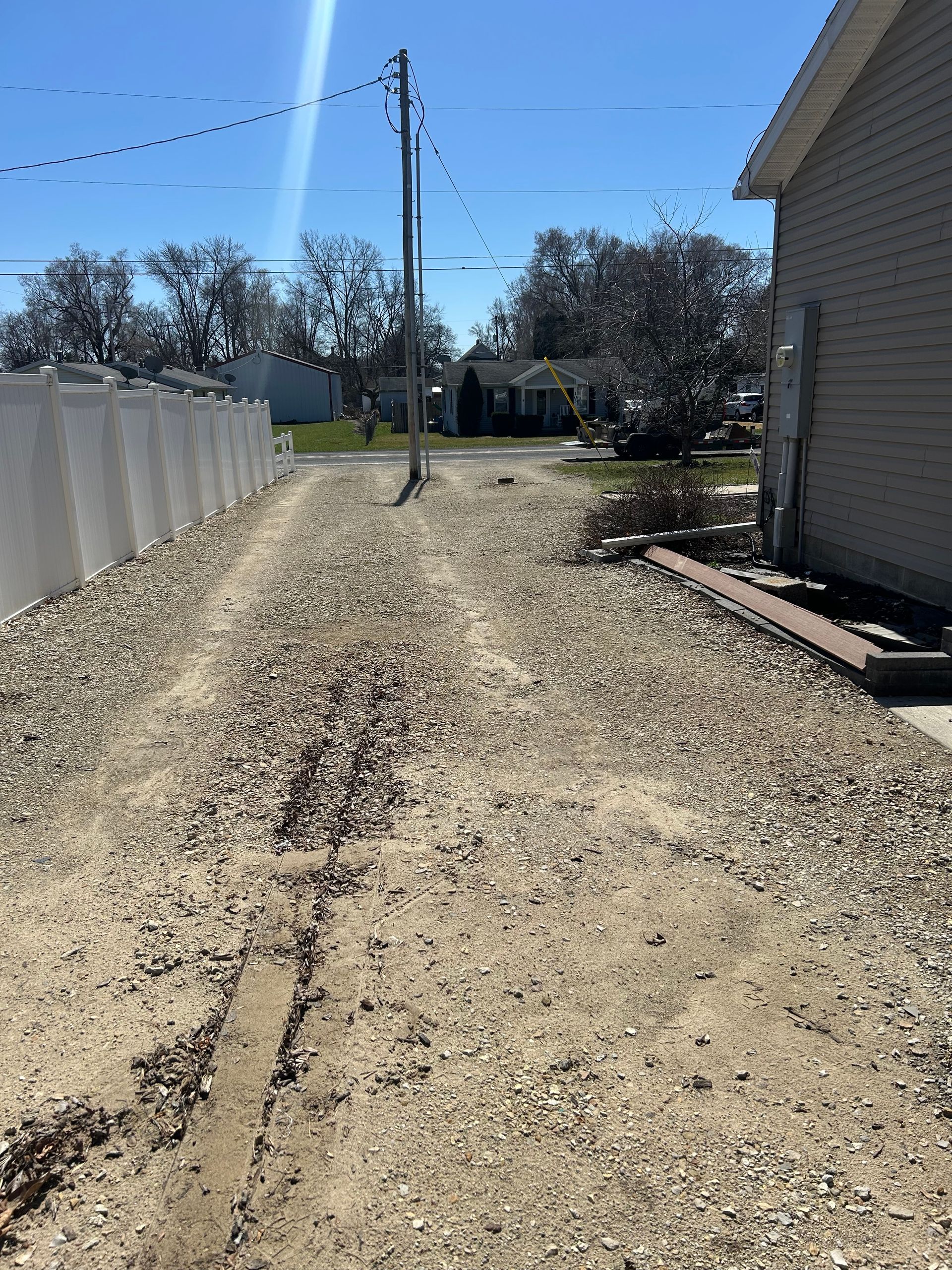 A dirt road with a house in the background