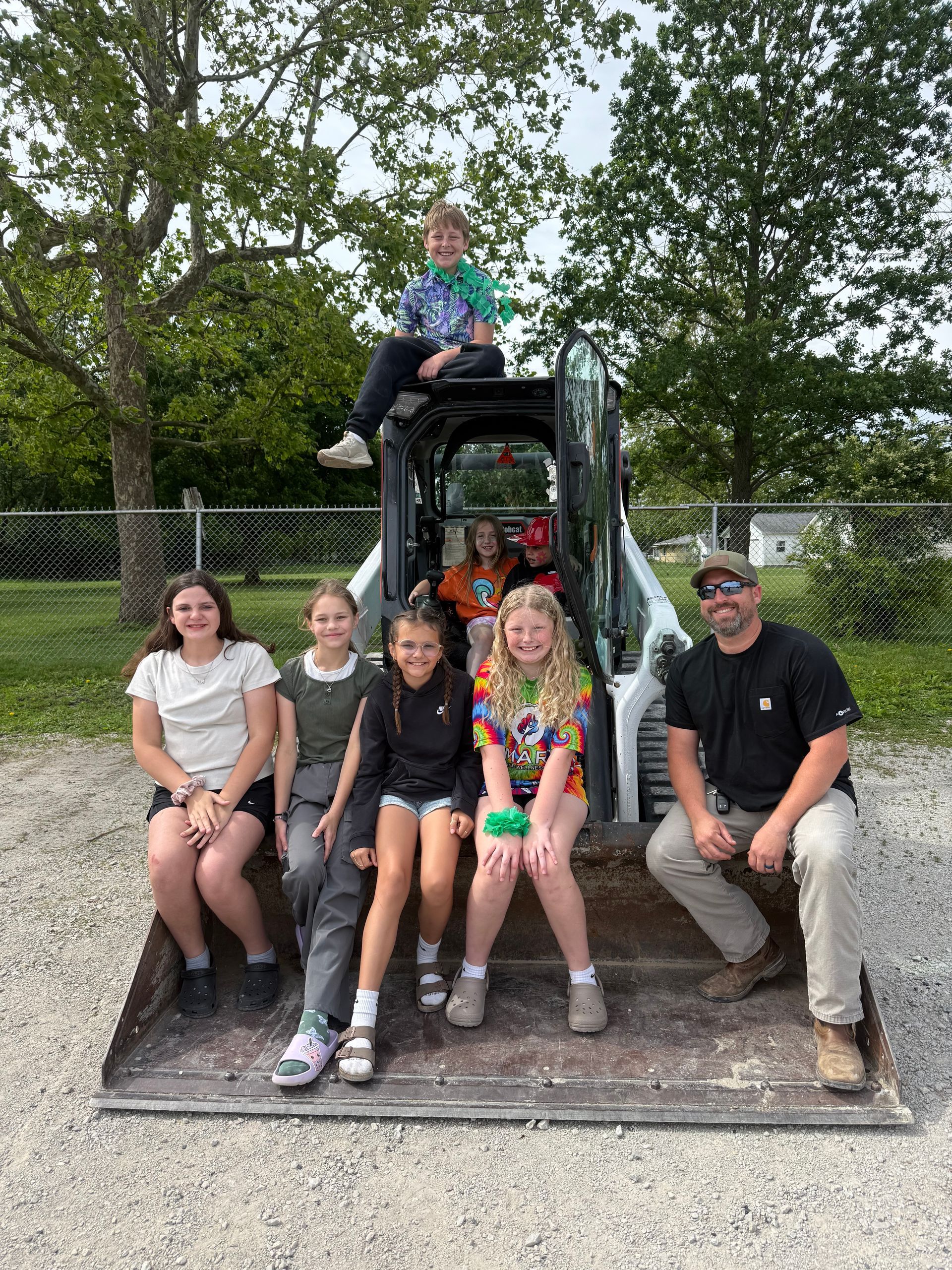 A group of people are sitting on top of a bulldozer. A group of people are sitting on top of a bulldozer.