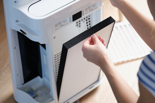 A person is changing a filter on an air purifier.