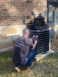 A man is working on an air conditioner outside of a brick building.
