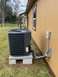An air conditioner is installed on the side of a house.