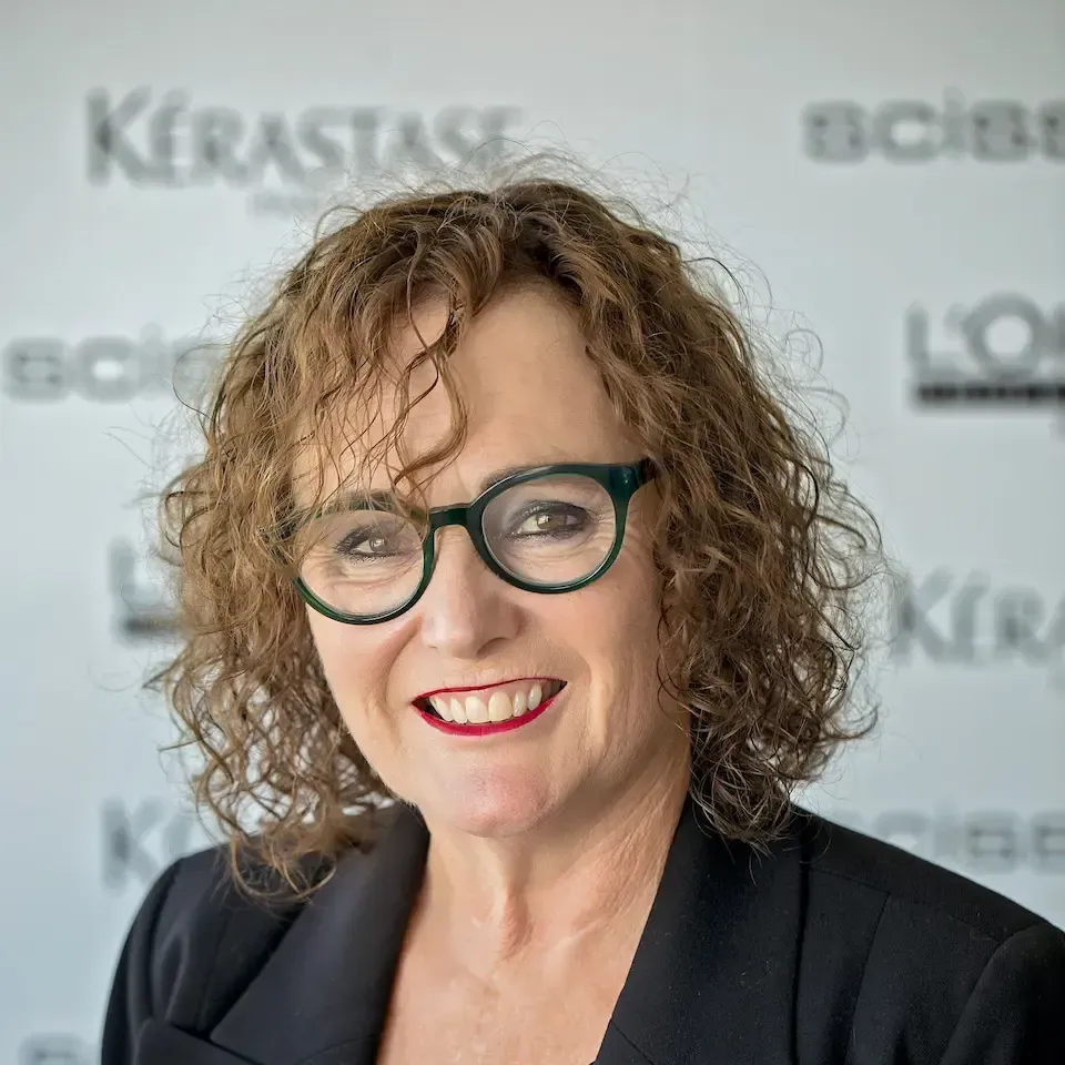 A woman wearing glasses and a black jacket is smiling for the camera.