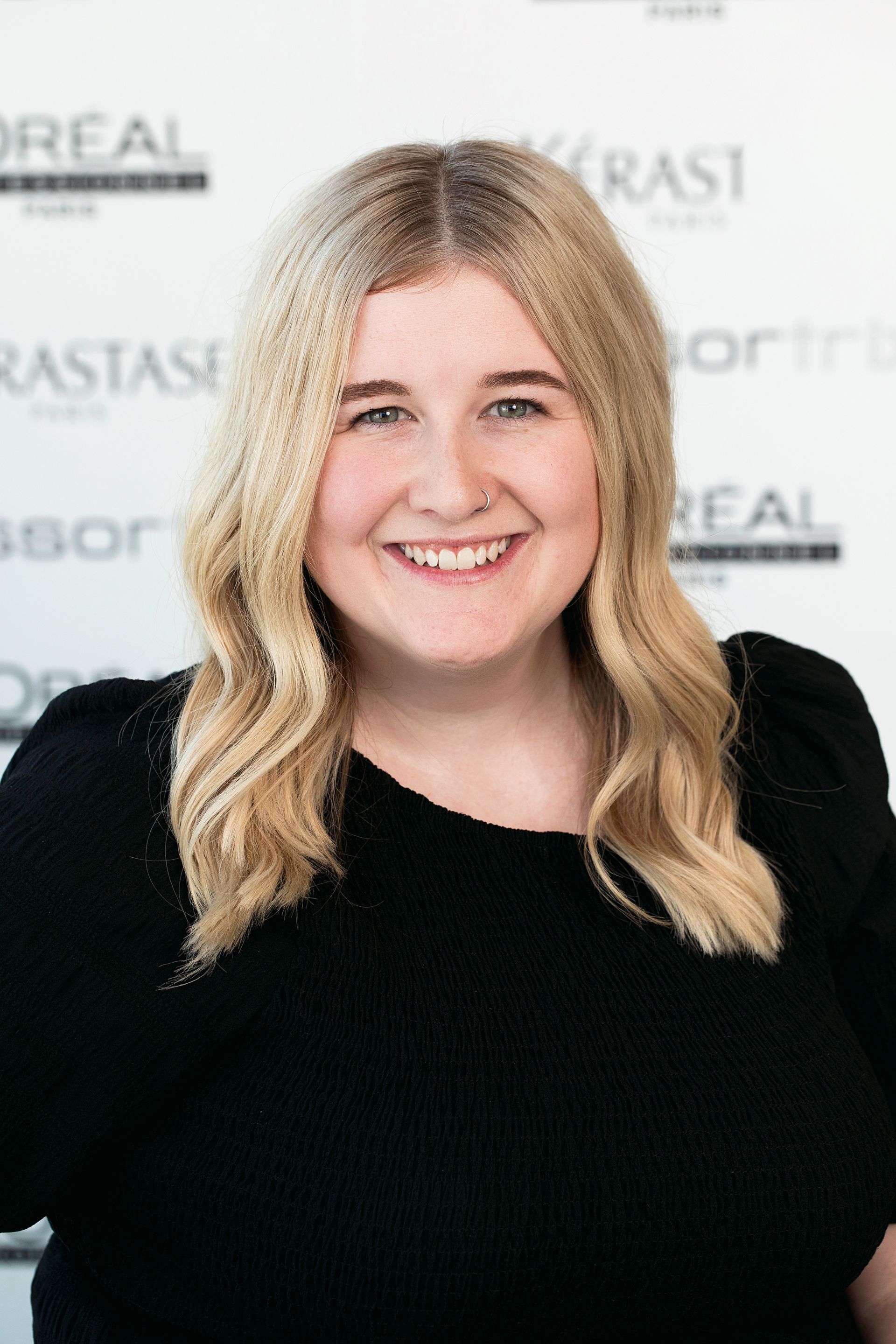A woman is smiling in front of a sign that says l' oreal