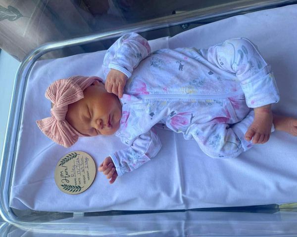 A newborn baby is sleeping in a hospital bed.