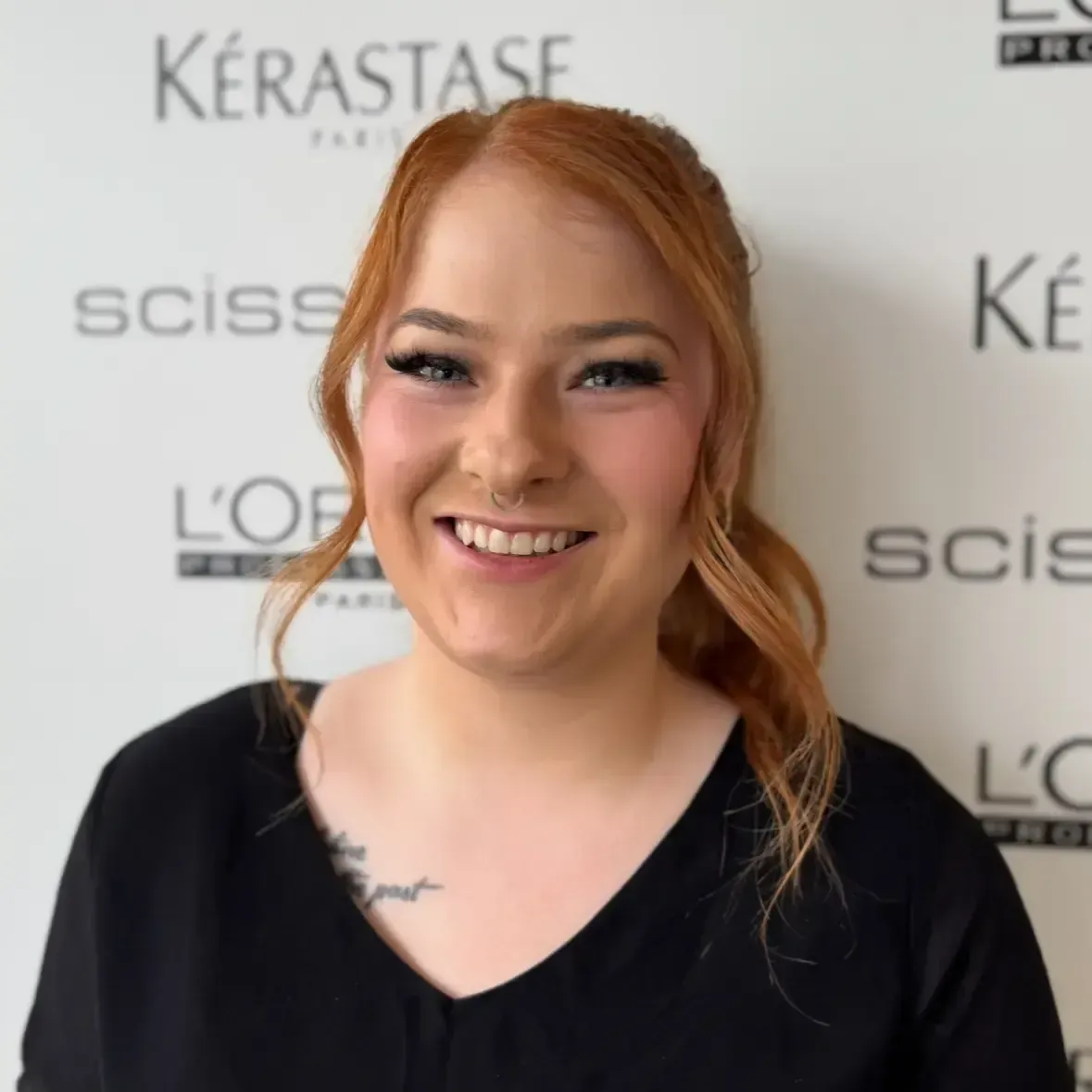 A woman with long hair is smiling in front of a loreal sign.