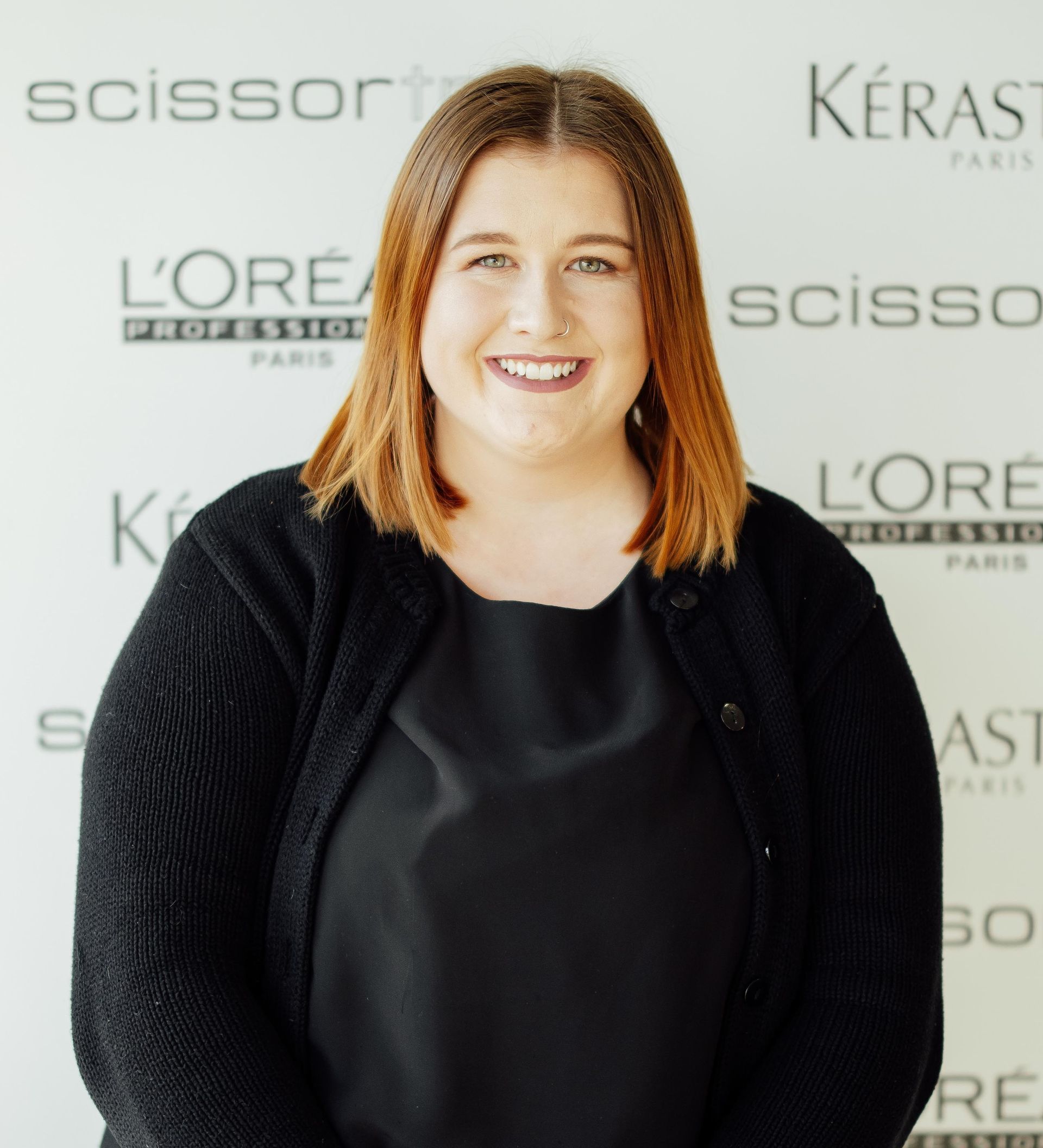 A woman stands in front of a wall that says scissors