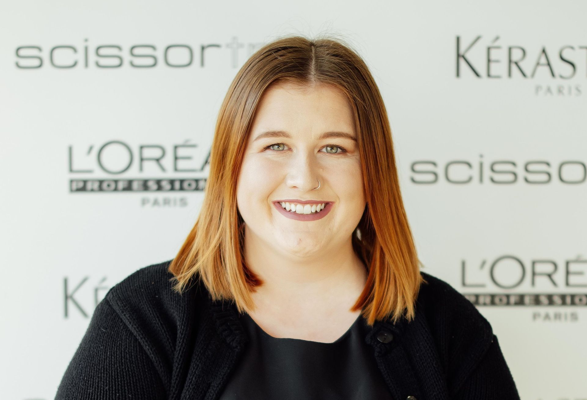 A woman stands in front of a wall with scissors and kerastase written on it