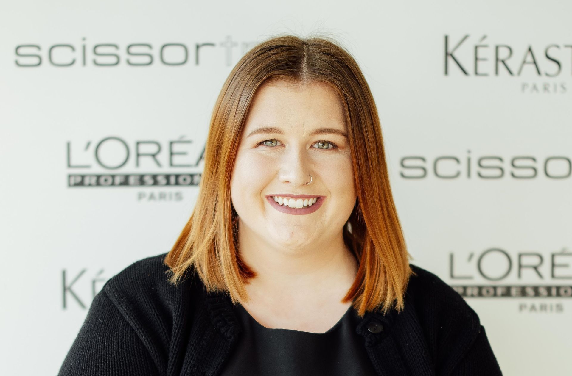 A woman stands in front of a wall with scissors and kerastase written on it