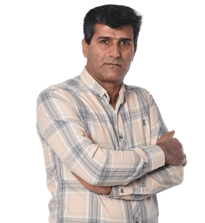 Man in plaid shirt with arms crossed, looking serious. White background.