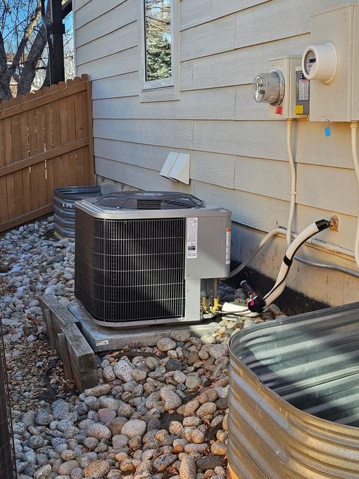 Central air conditioning unit next to a house, with electrical box visible.