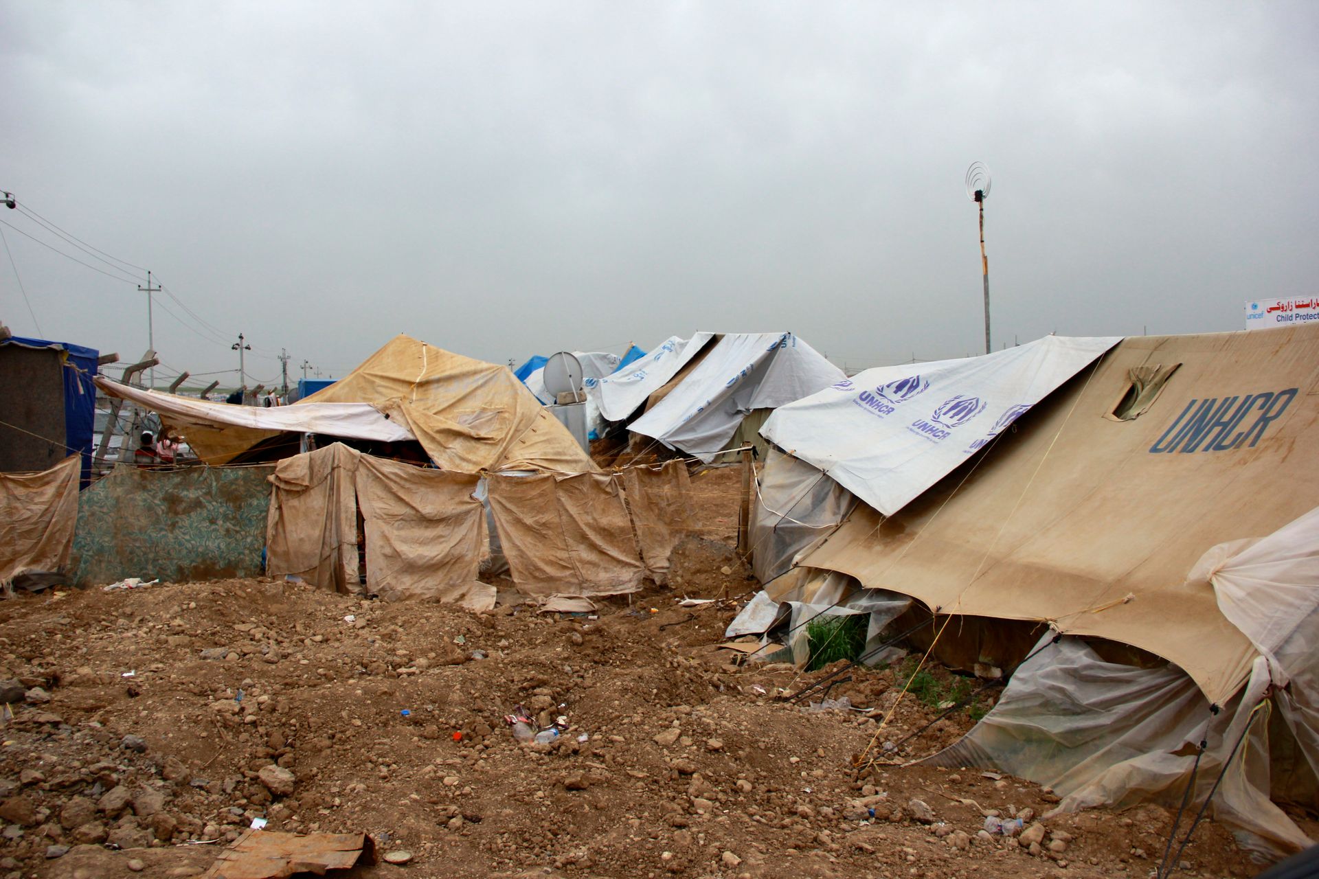A row of tents are sitting on top of a dirt field.