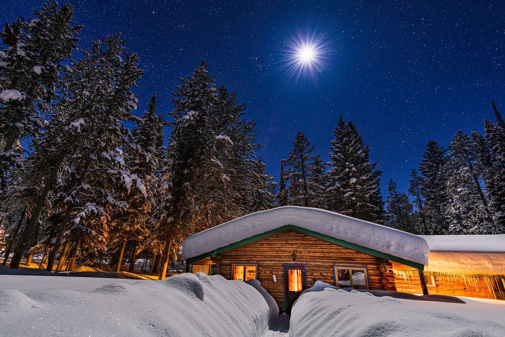 A log cabin in the middle of a snowy forest at night