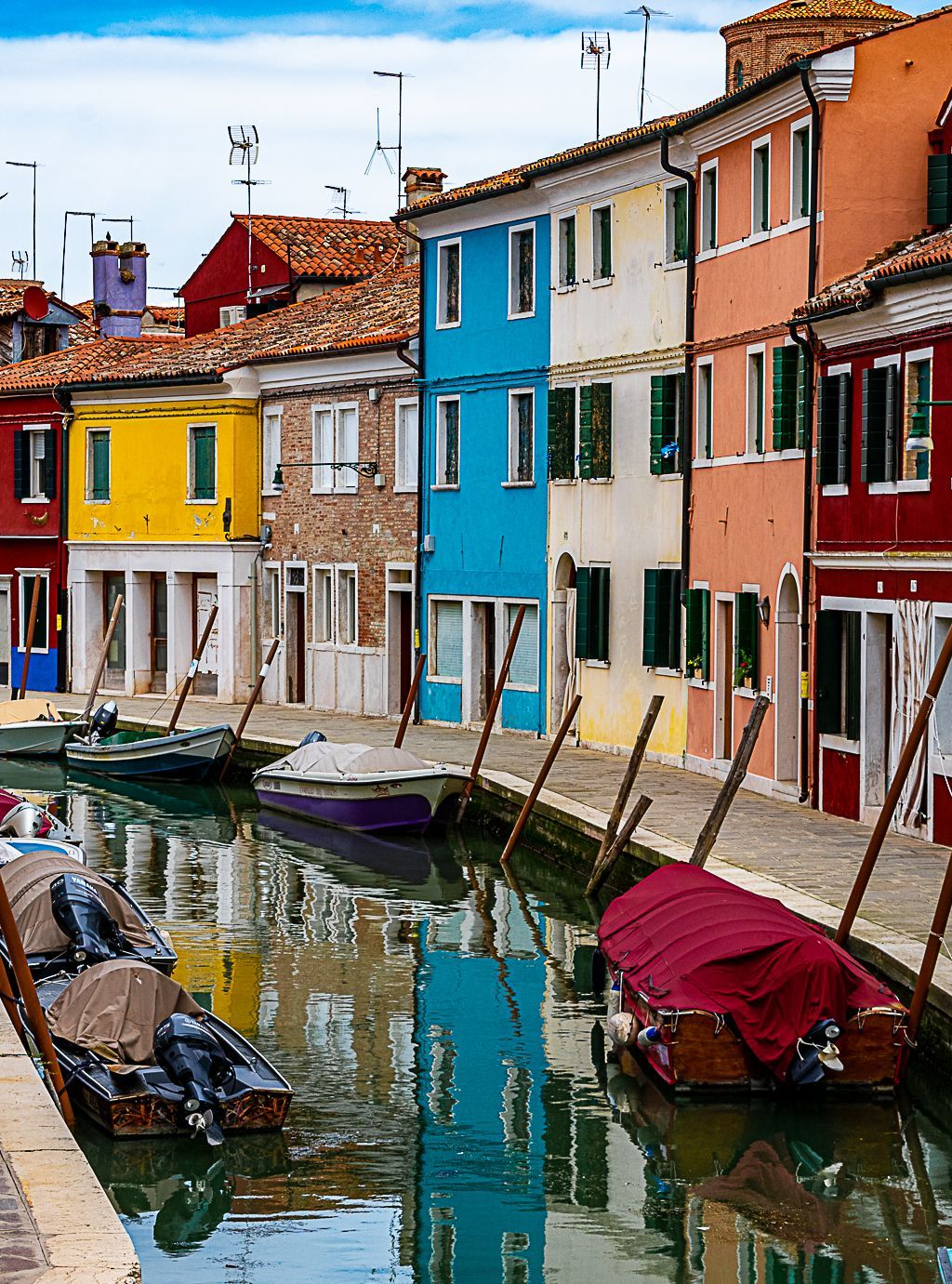 A row of colorful buildings along a canal with boats in the water