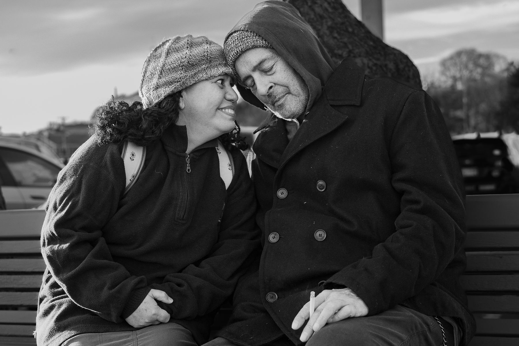 a man and a woman are sitting on a bench looking at each other .