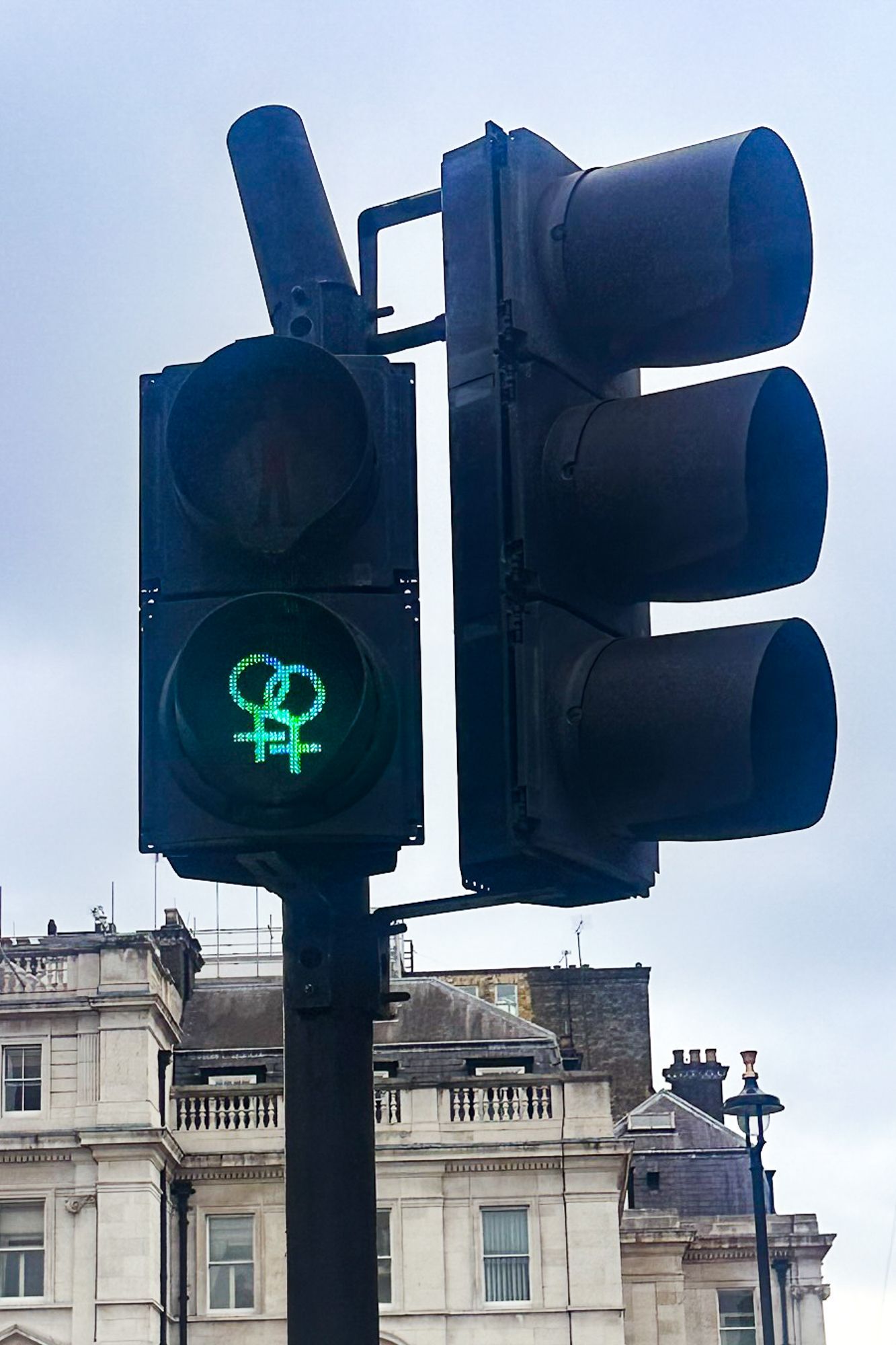 A traffic light with a green female symbol on it