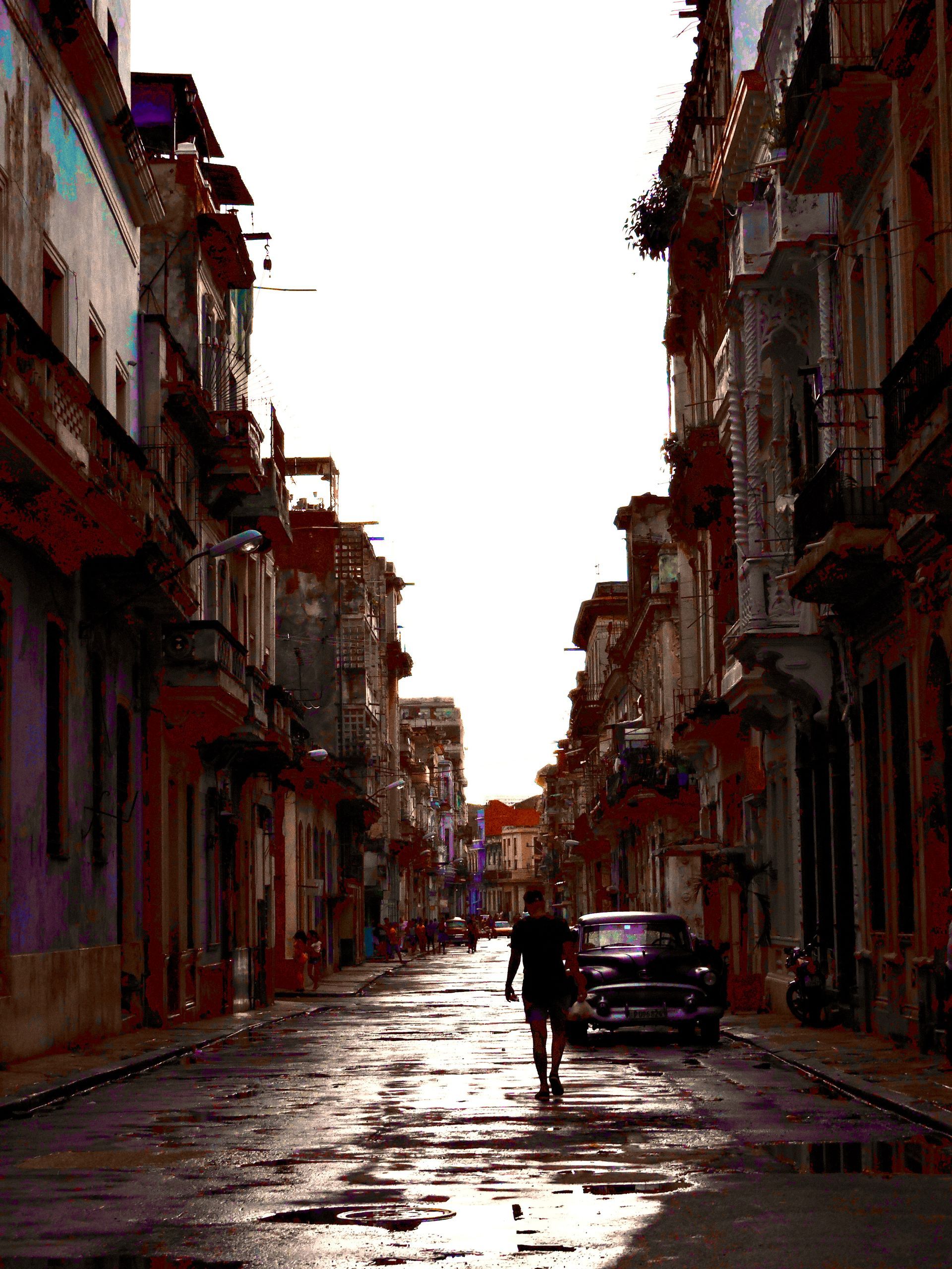 A narrow street with a car parked on the side of it