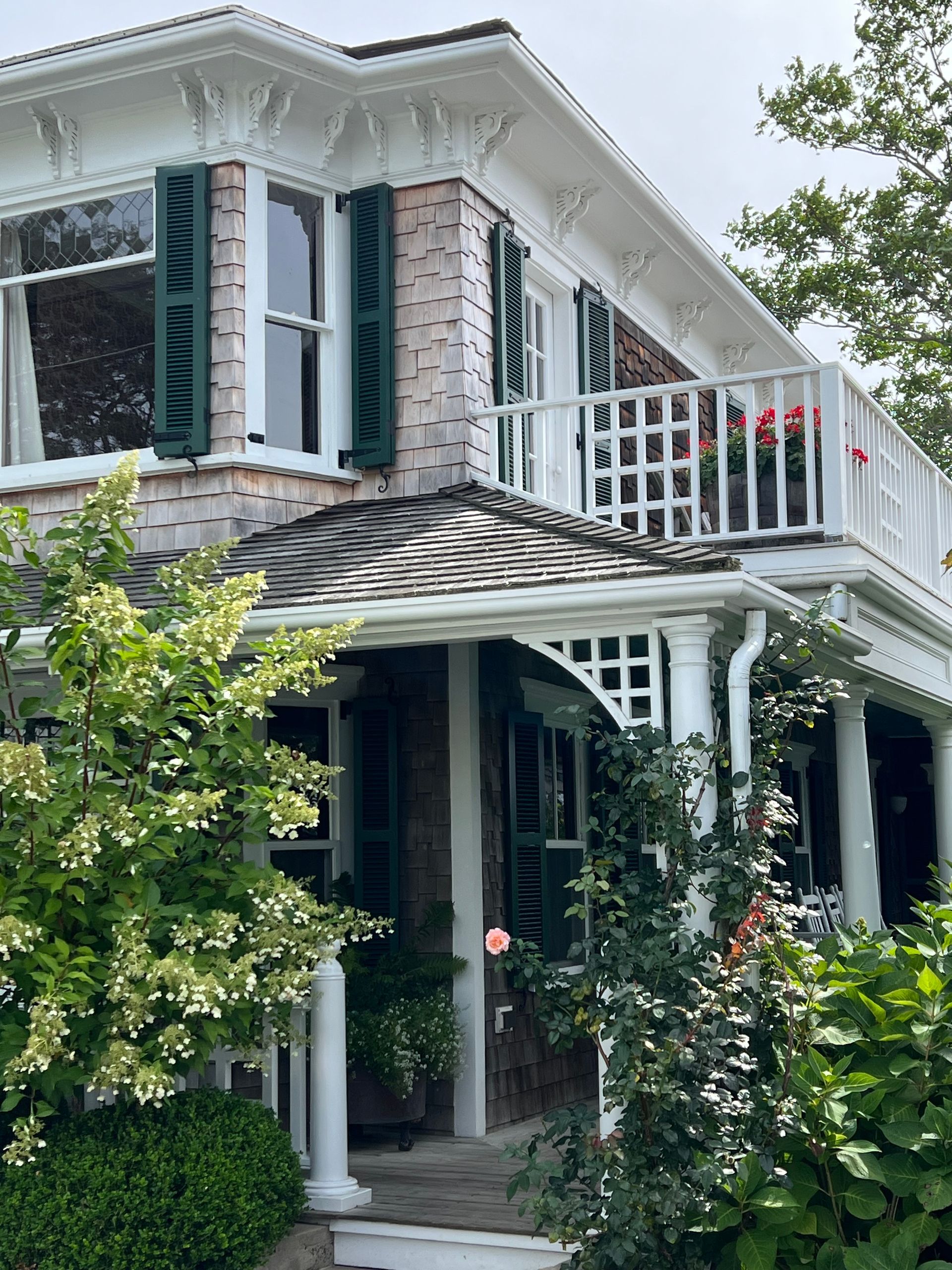 a brick house with a balcony and green shutters