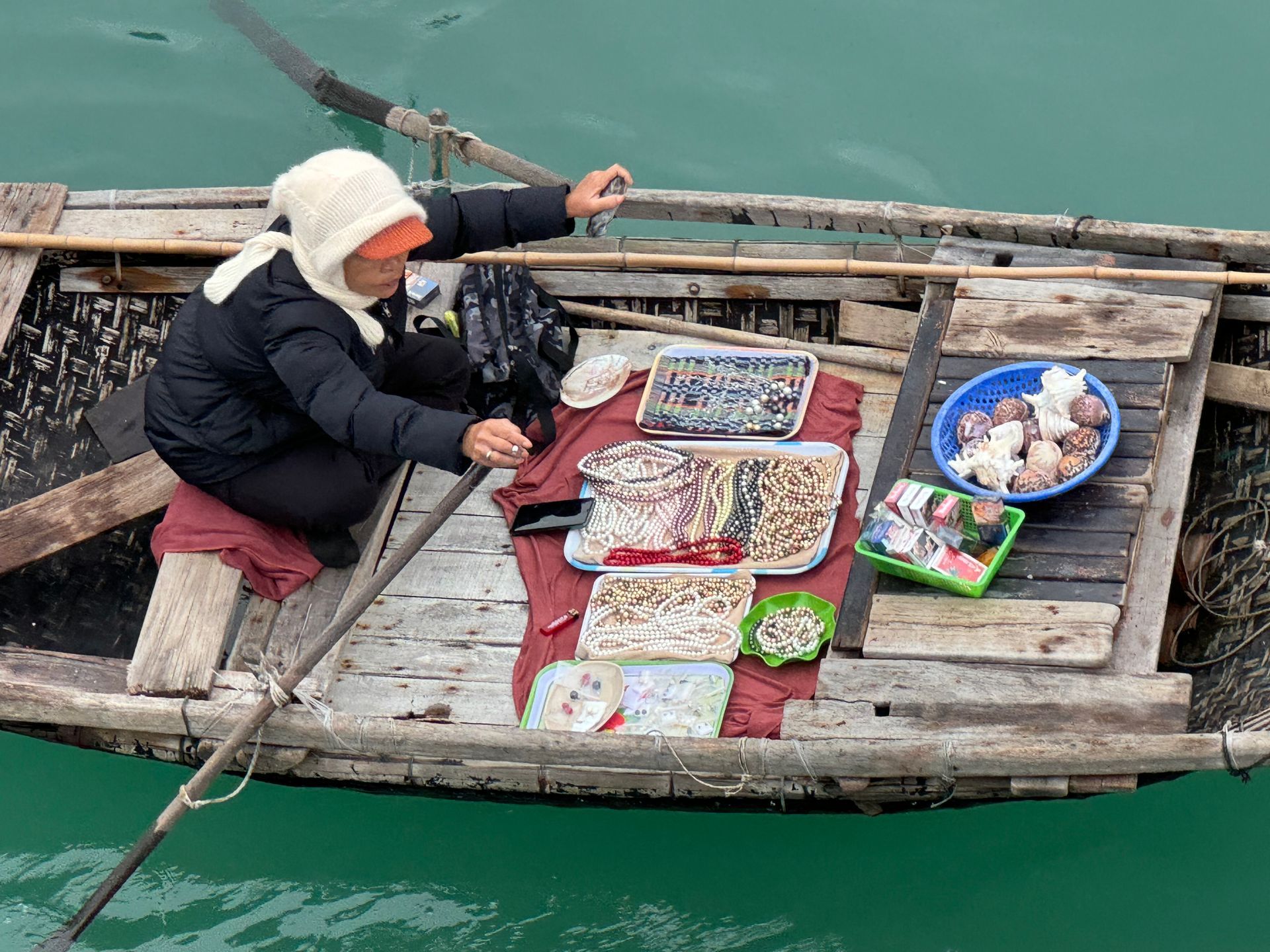 A woman is selling food from a boat in the water.