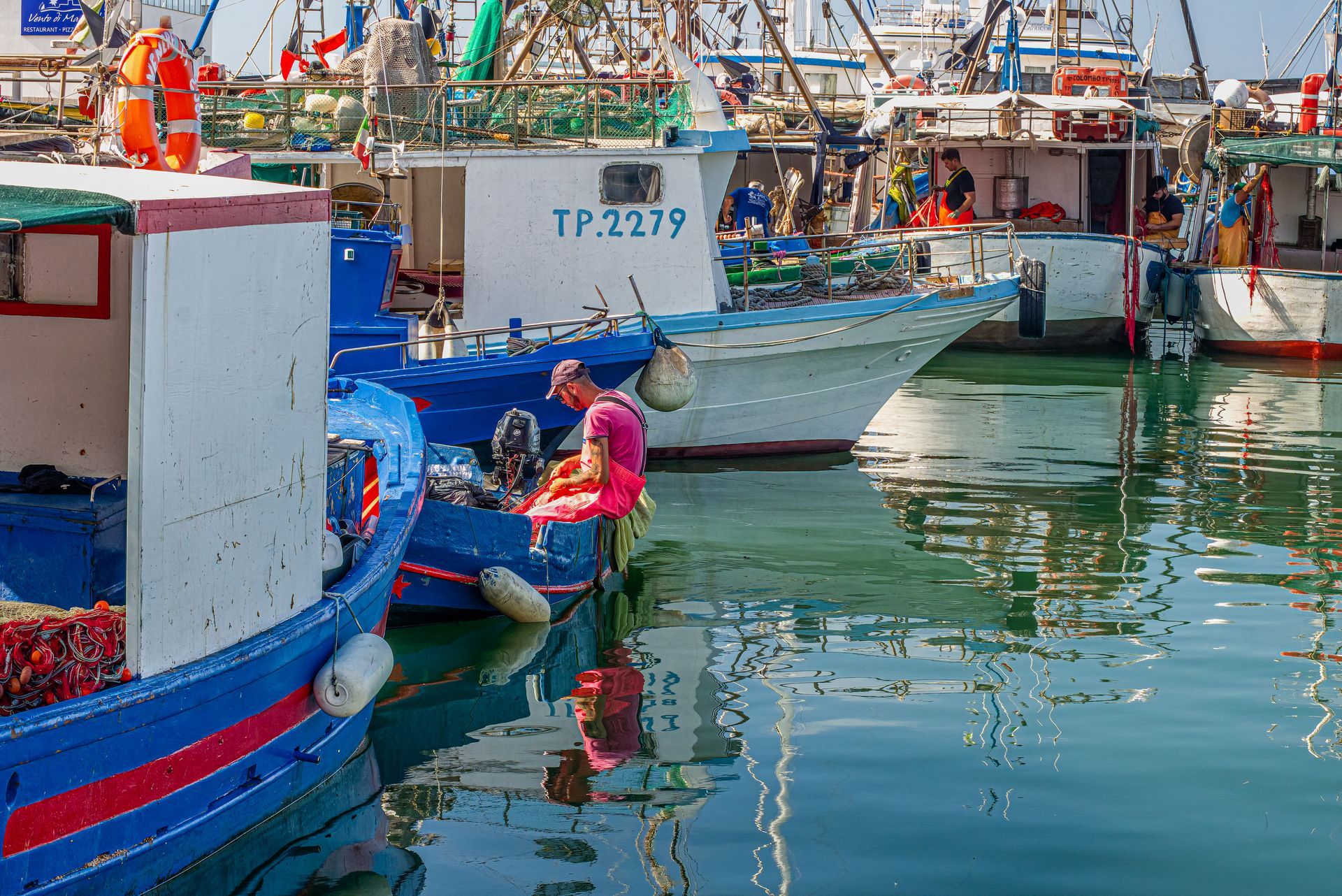 A woman is sitting on a boat in a harbor.