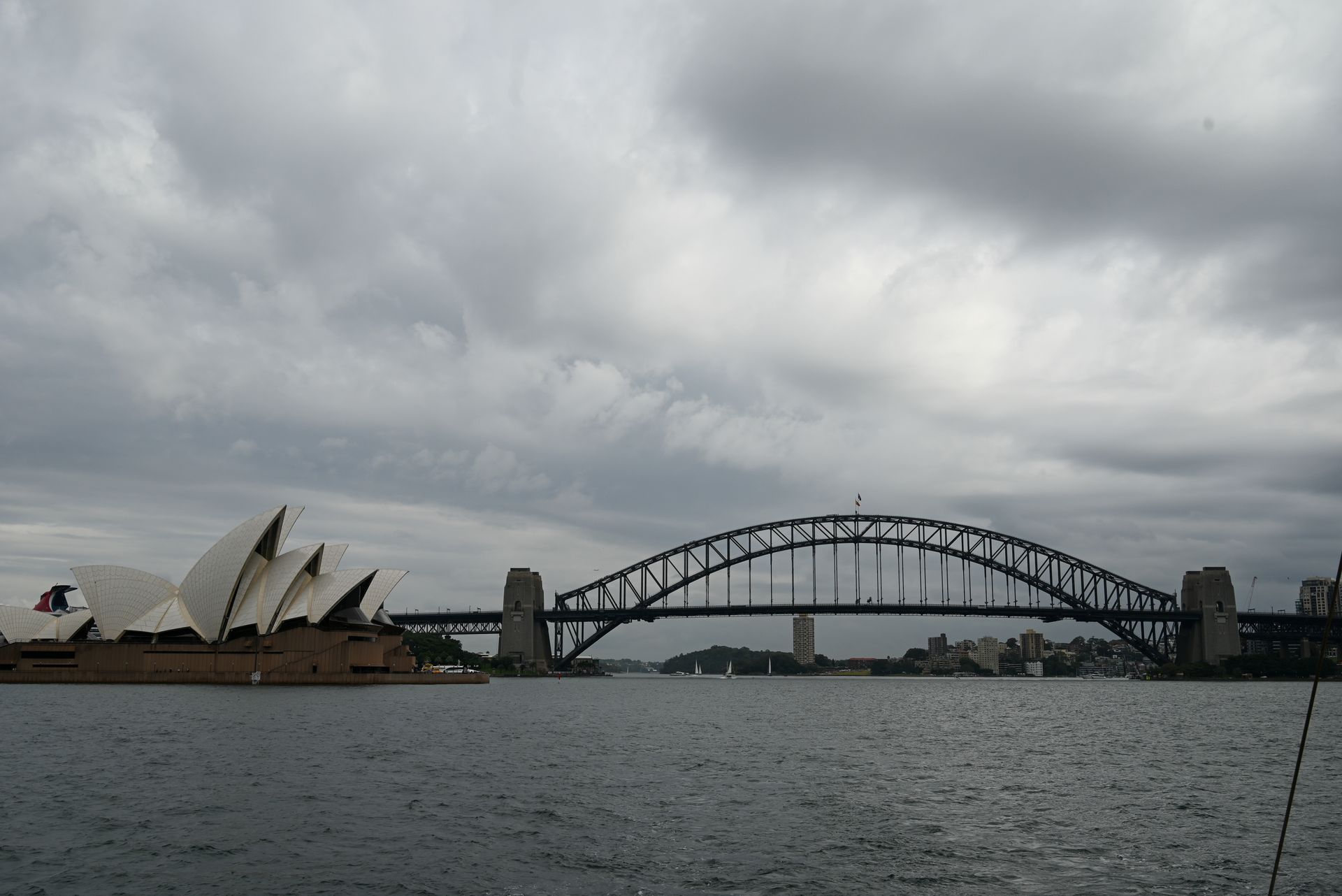 A bridge over a body of water with the opera house in the background