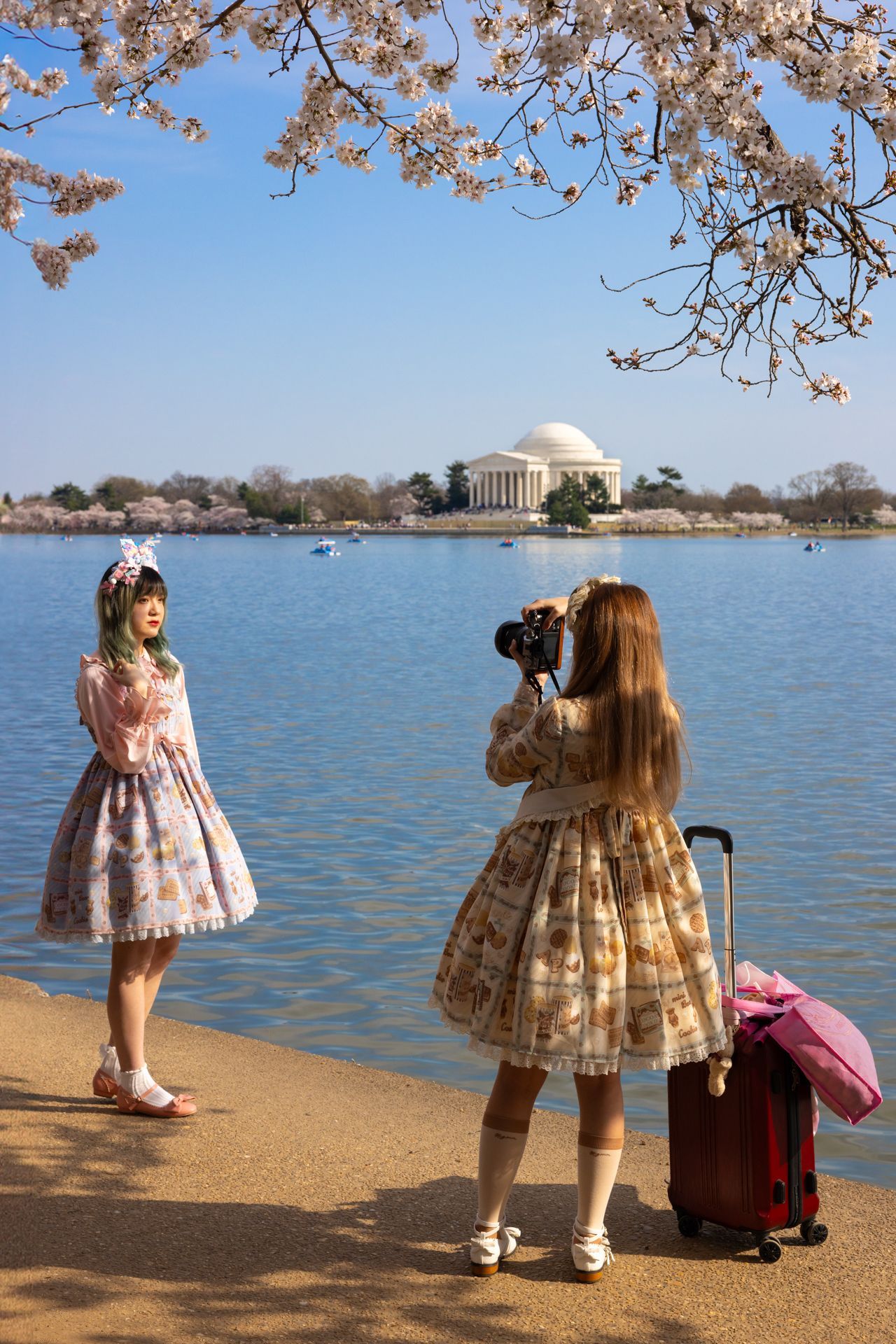 A woman is taking a picture of another woman by the water.
