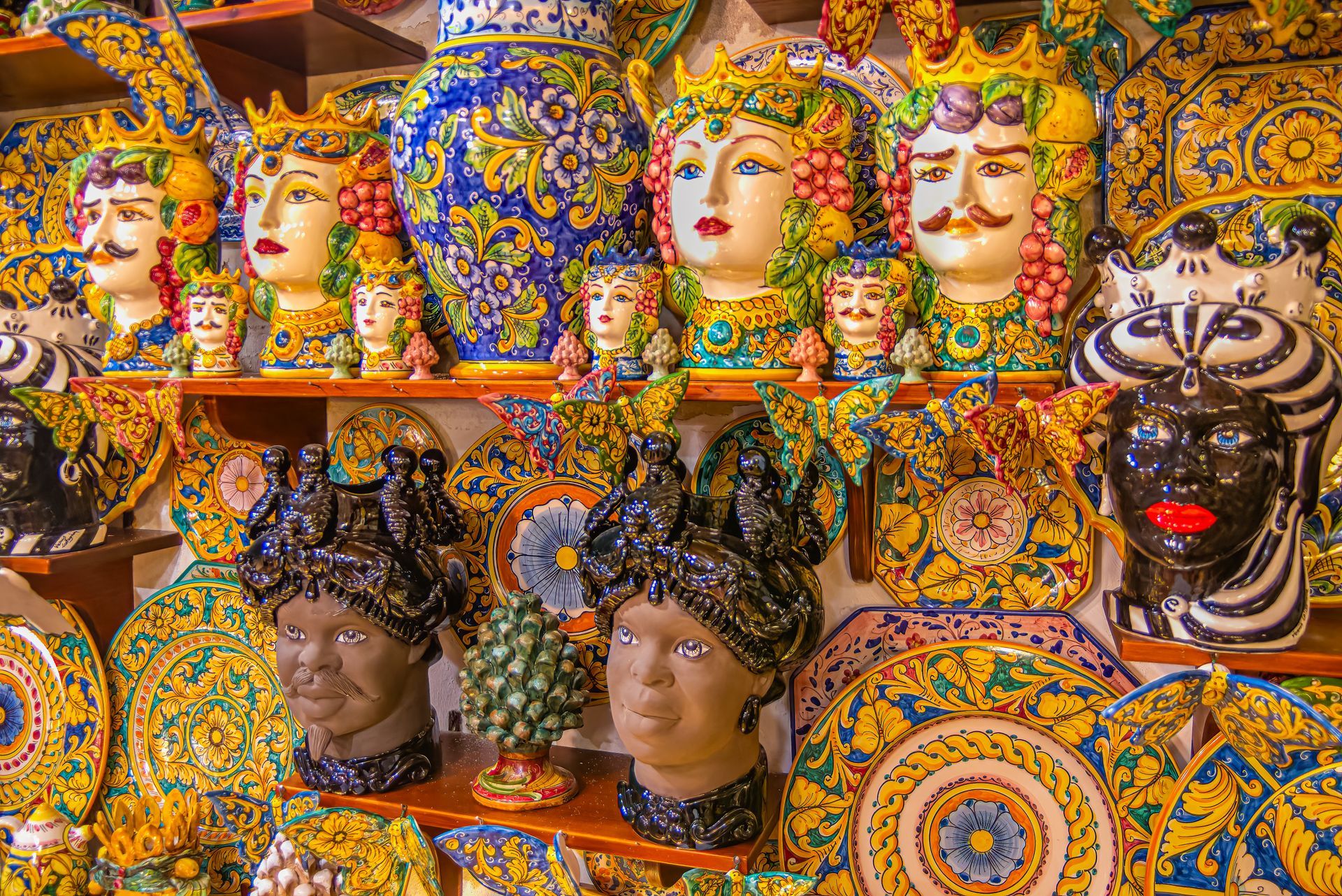A shelf filled with vases and plates with heads on them.