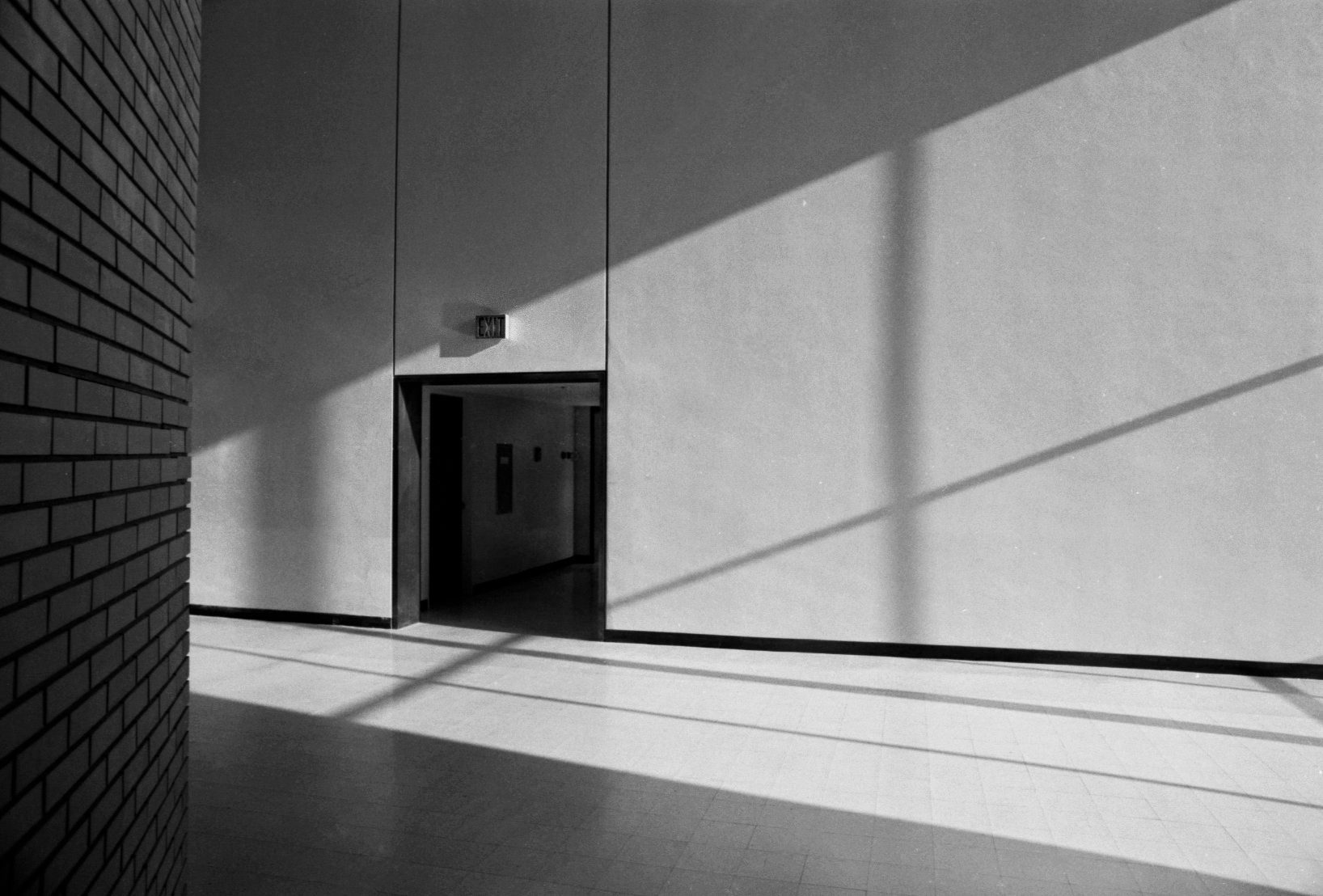 A black and white photo of a hallway with a brick wall