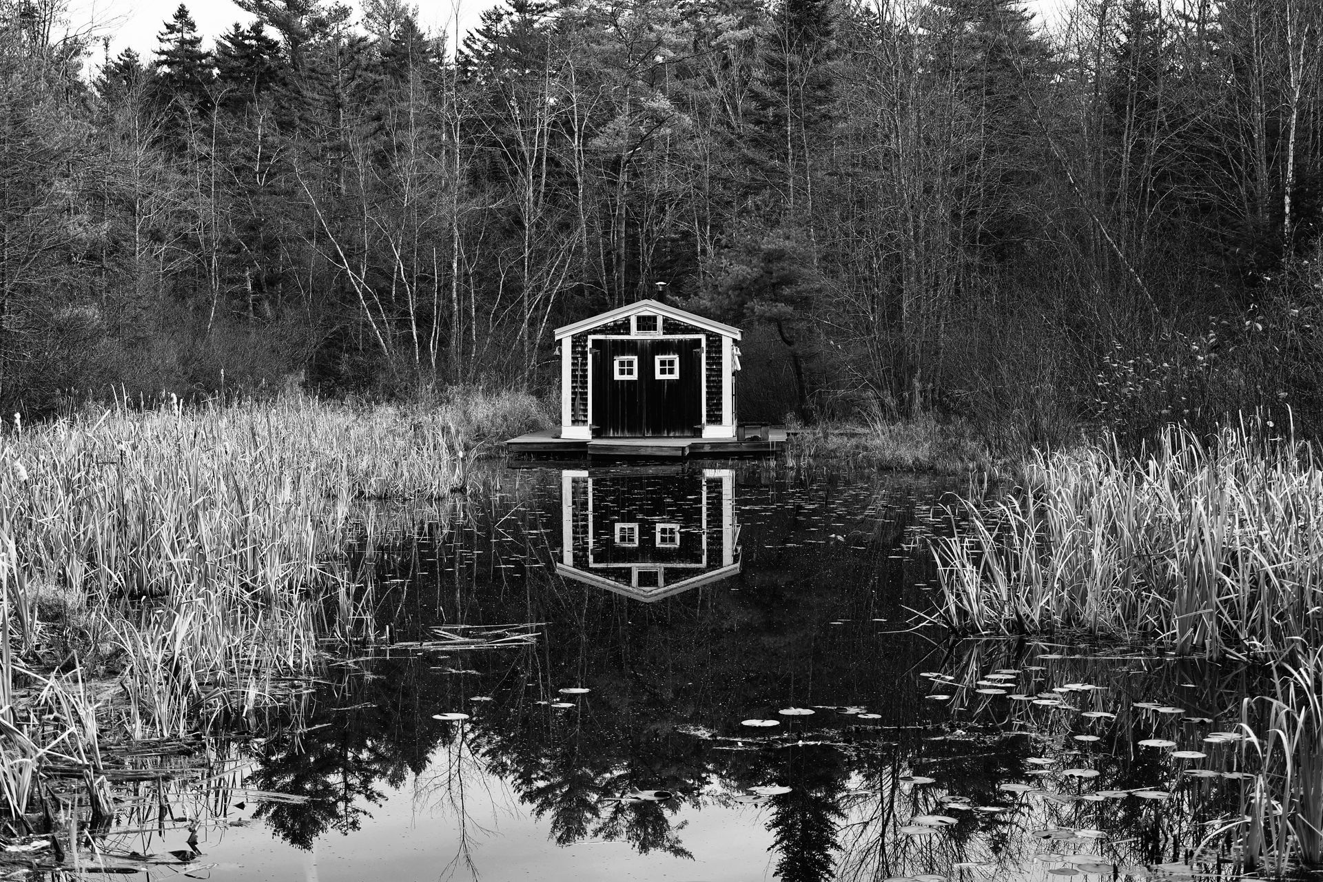 A black and white photo of a shed in the middle of a lake