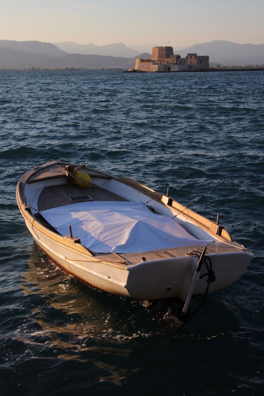 A small boat is floating on the water with a castle in the background