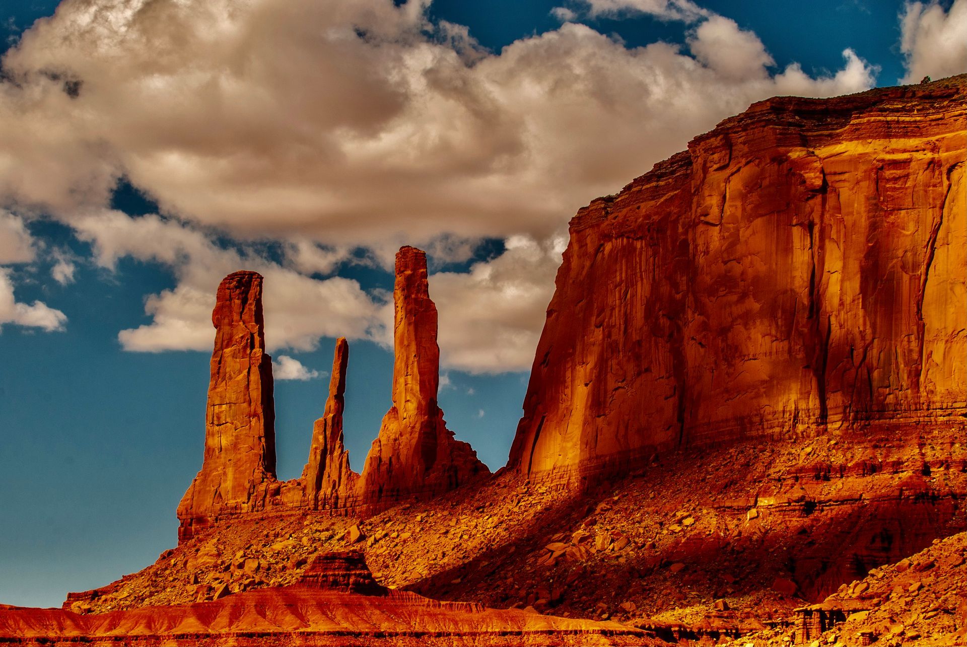 A rock formation in the desert with a blue sky and clouds in the background