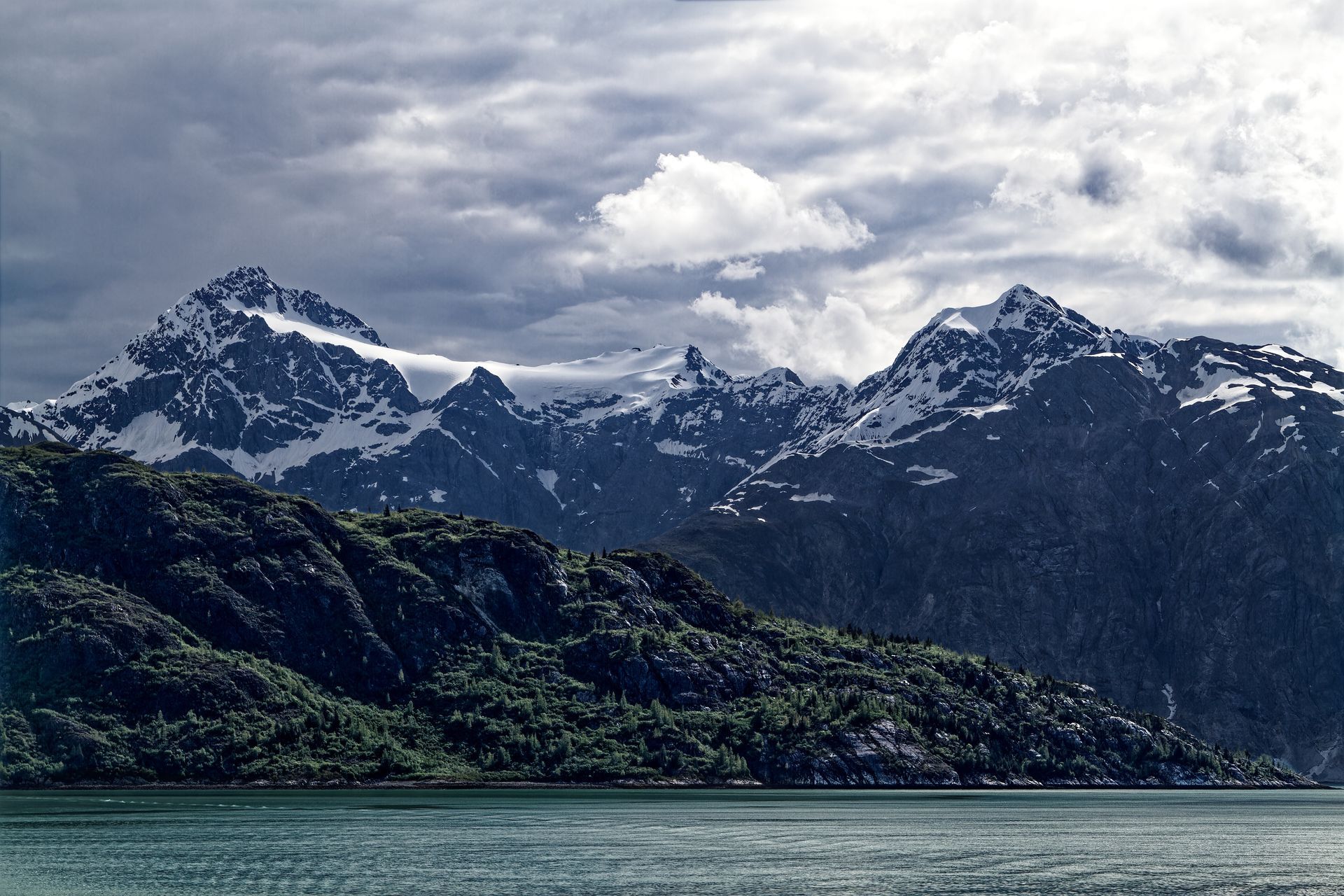 A lake with mountains in the background and a cloudy sky