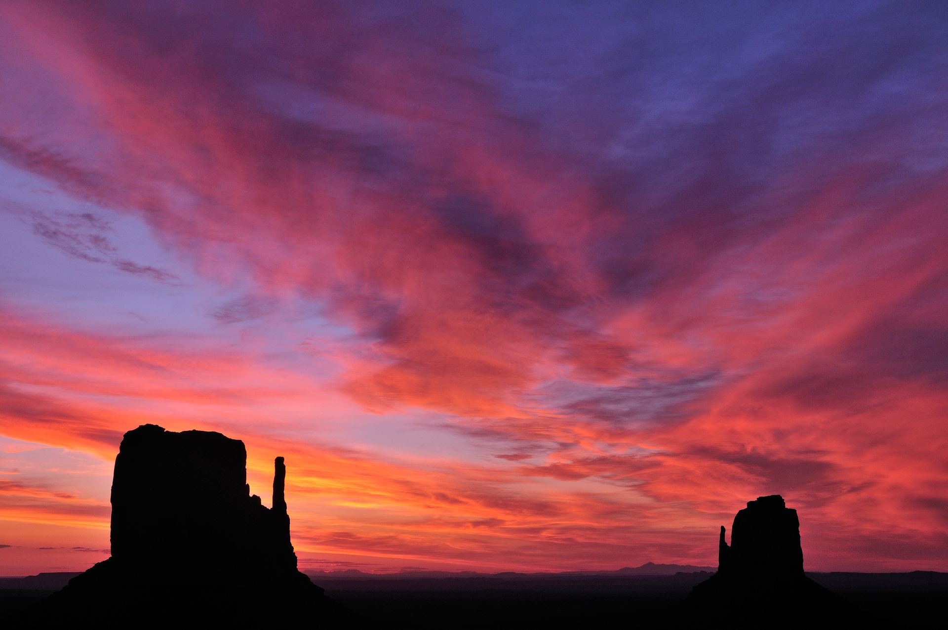 A couple of mountains silhouetted against a colorful sunset sky.