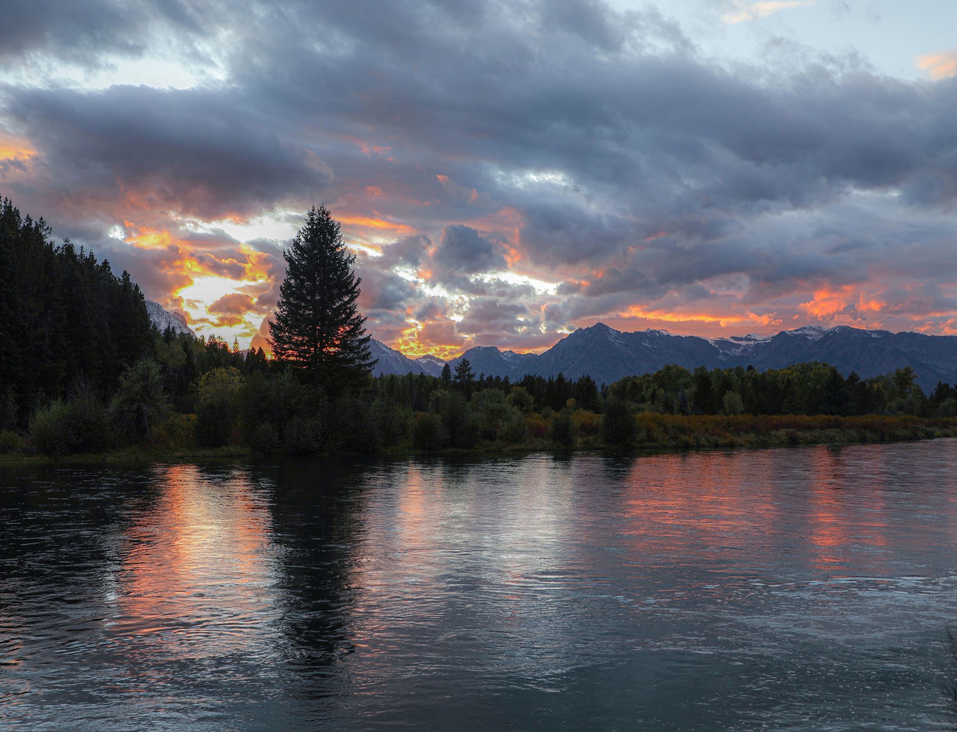 A sunset over a lake with mountains in the background
