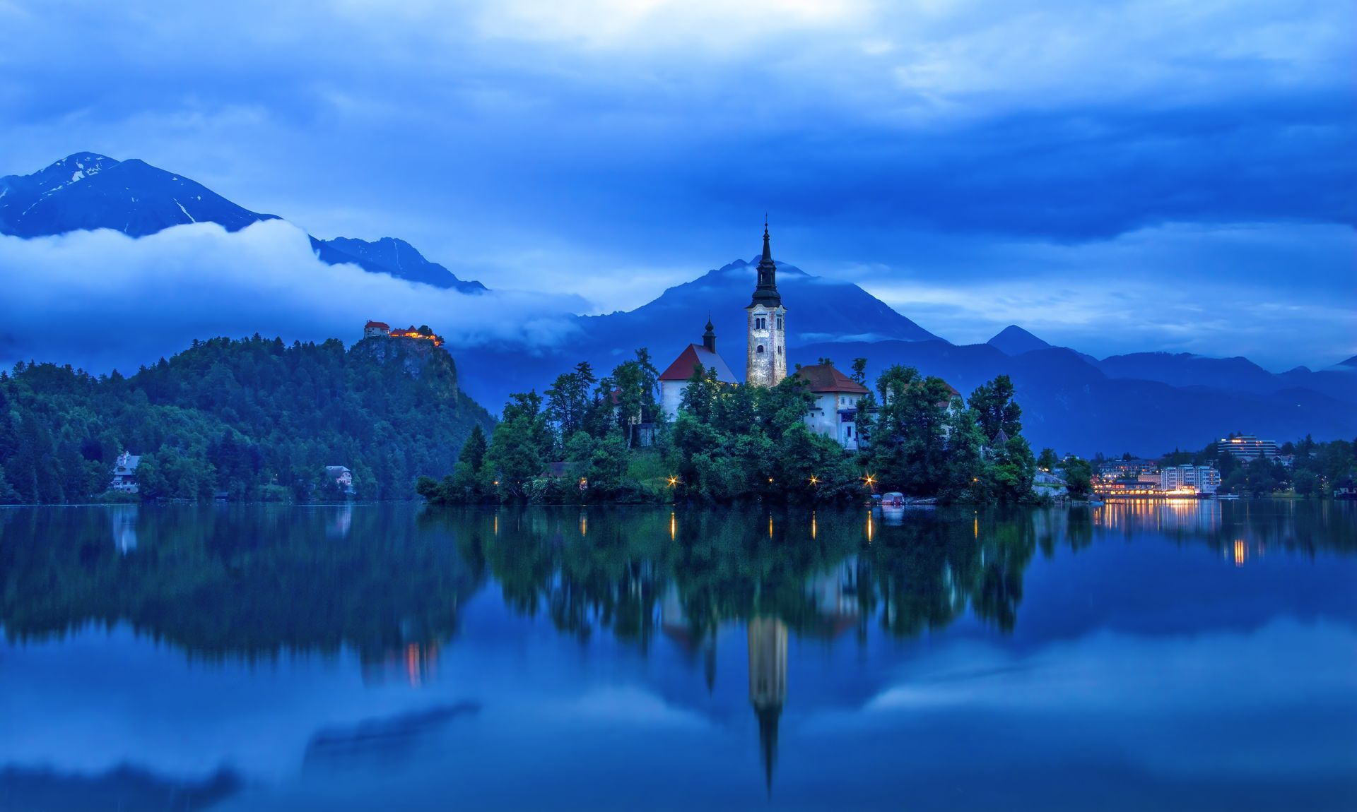 A small island in the middle of a lake with mountains in the background.