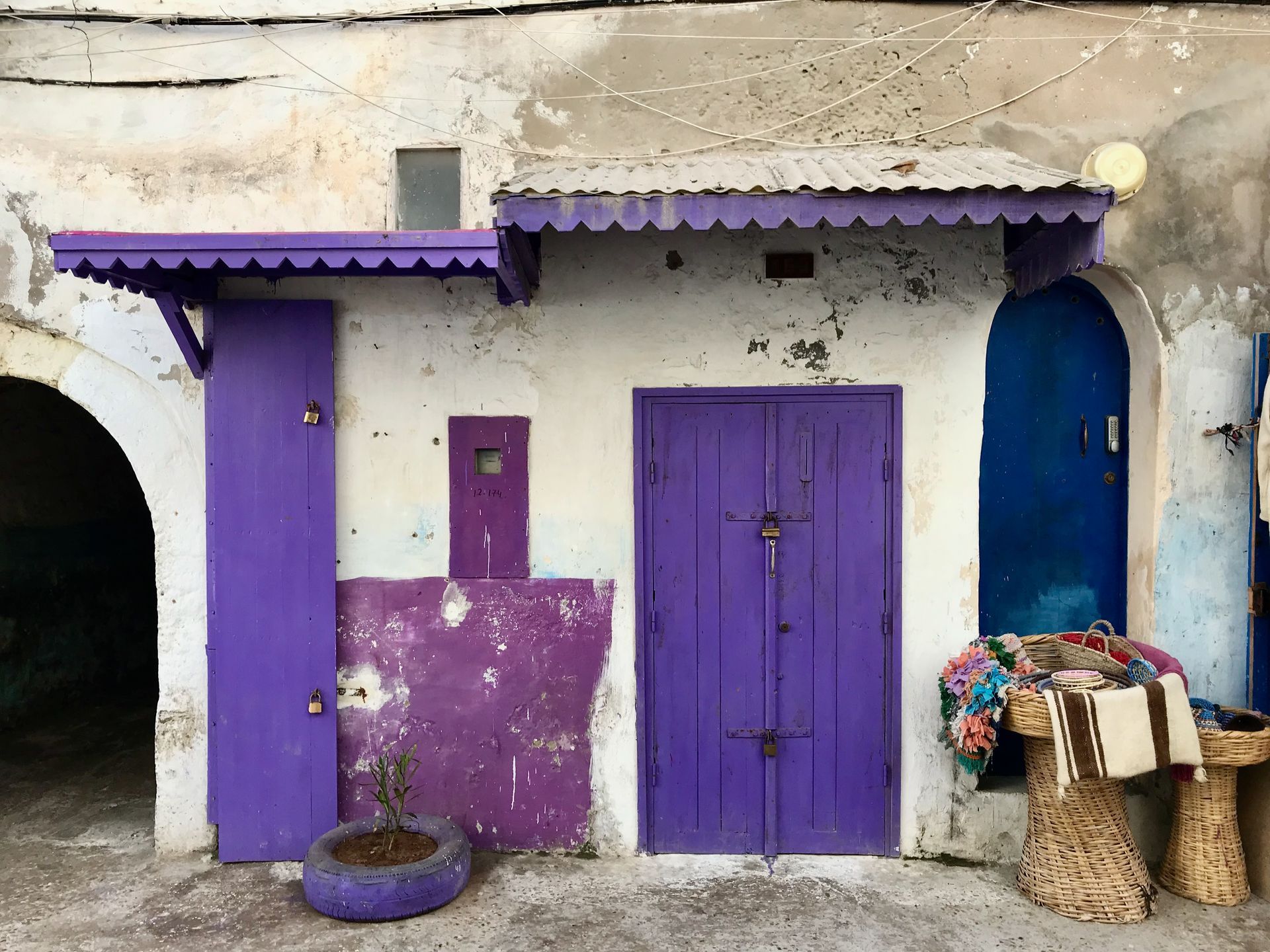 A white building with purple doors and a blue door.
