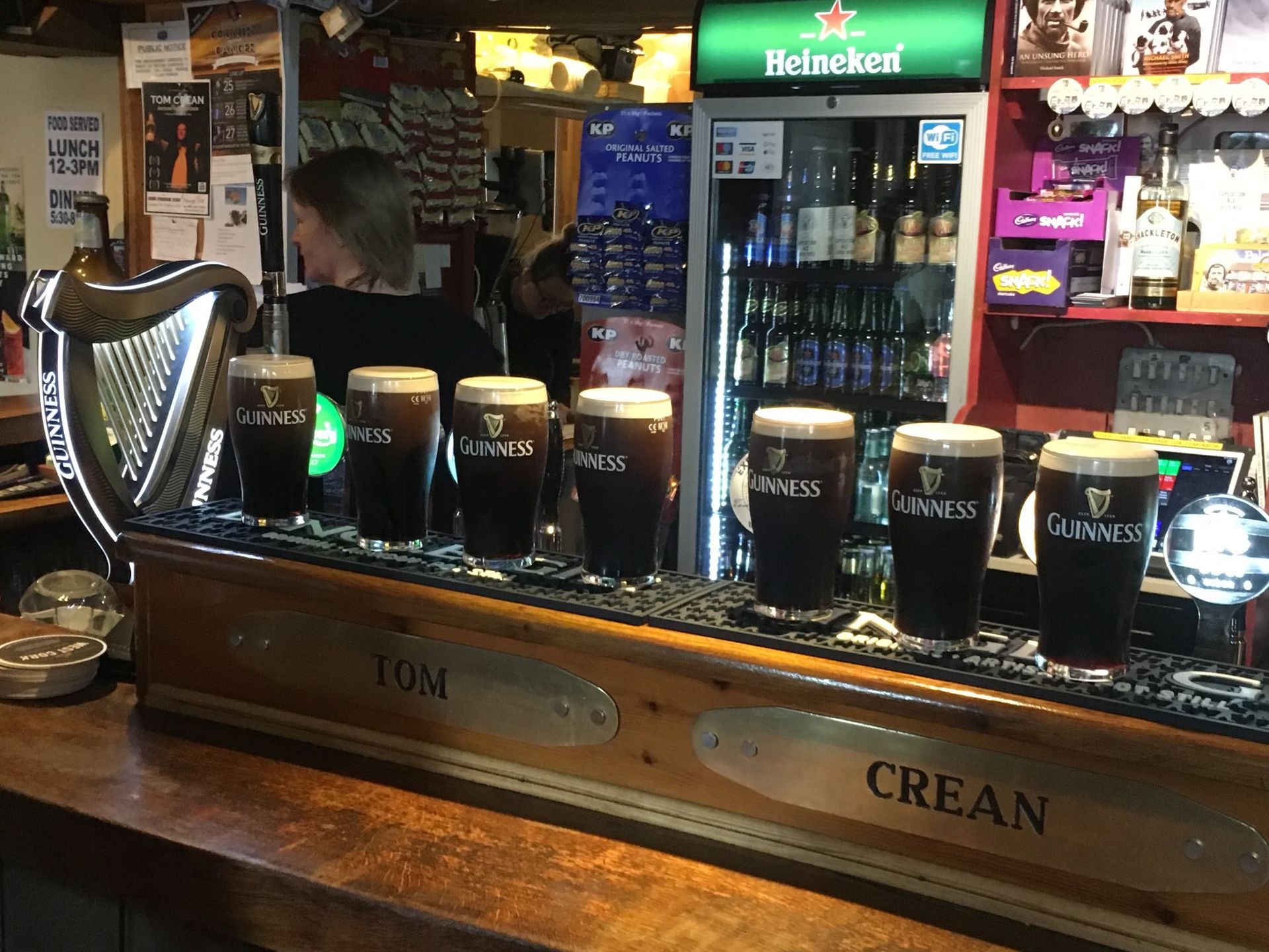 A row of guinness glasses are lined up on a bar.