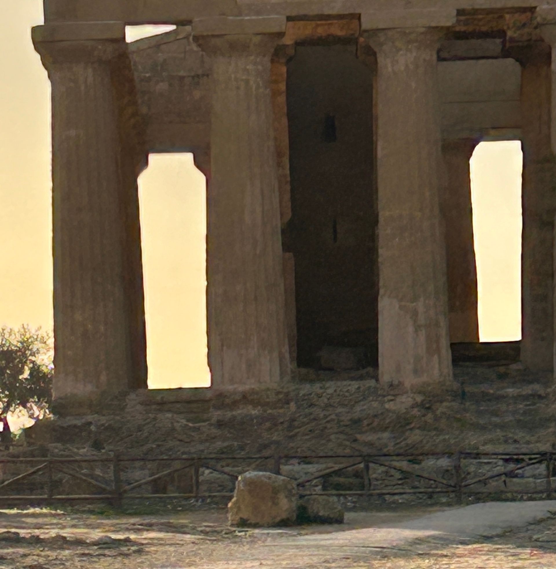 A very old building with columns and a fence in front of it.