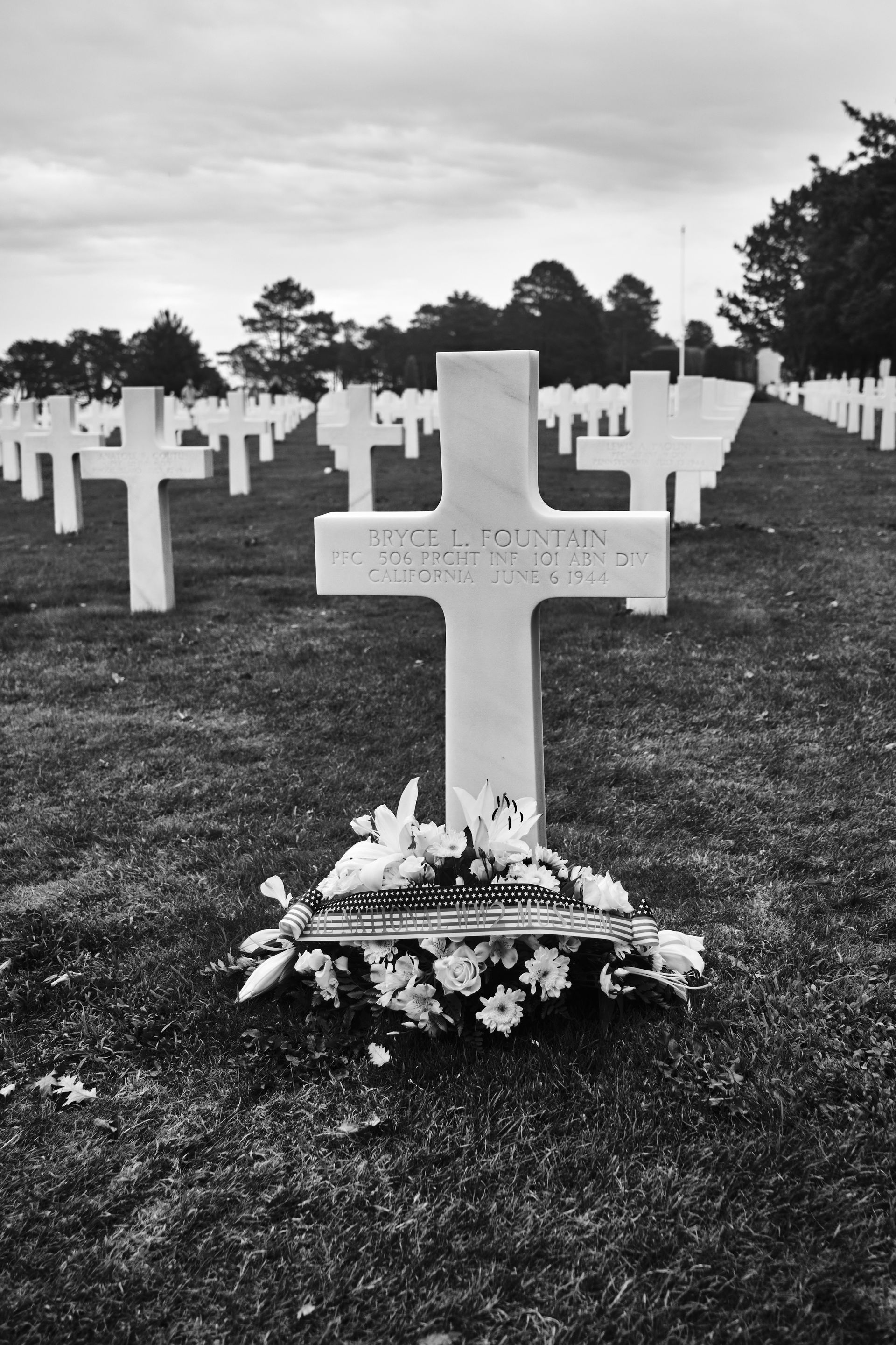 A black and white photo of a cross in a cemetery