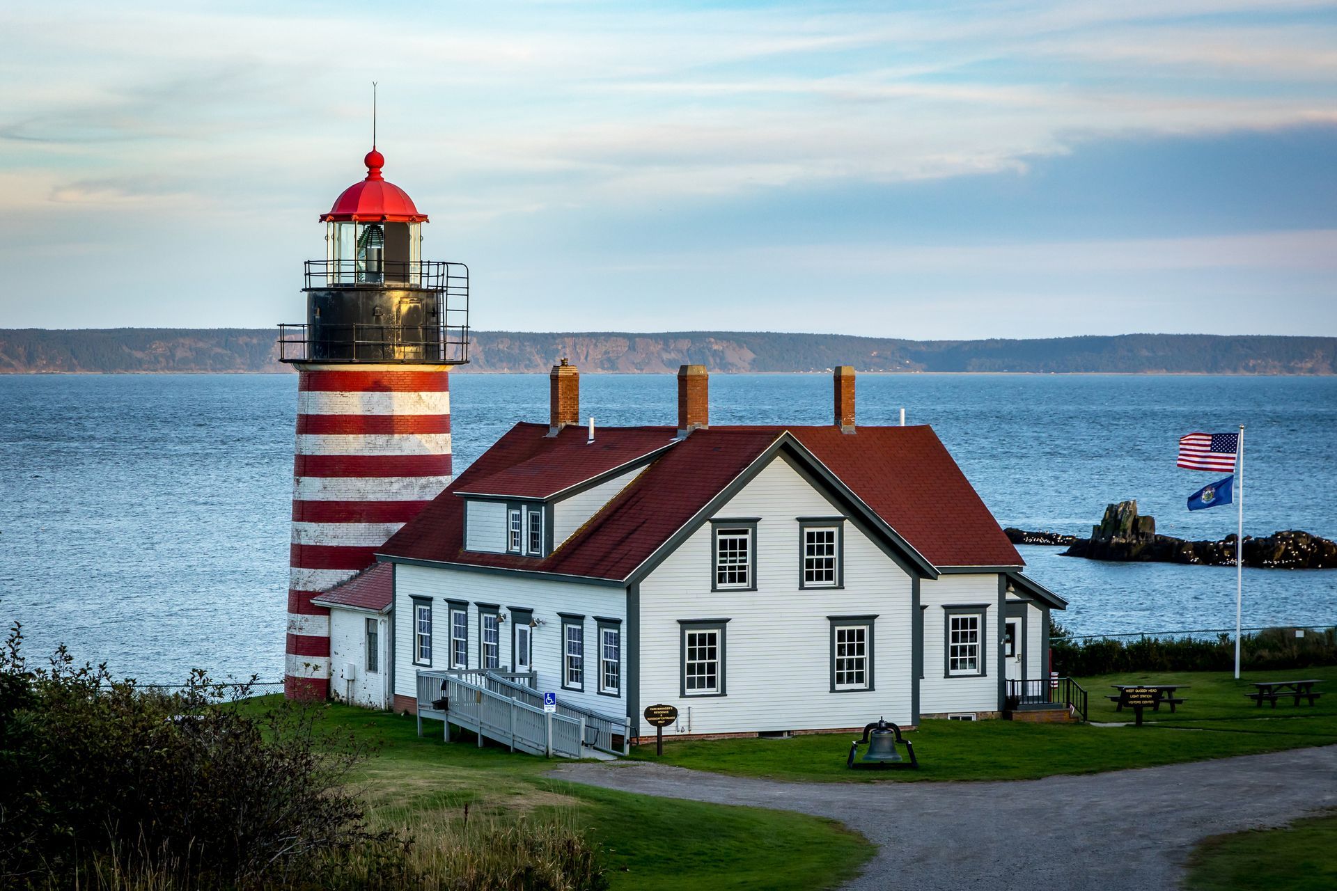 A red and white lighthouse sits on the shore of a body of water.