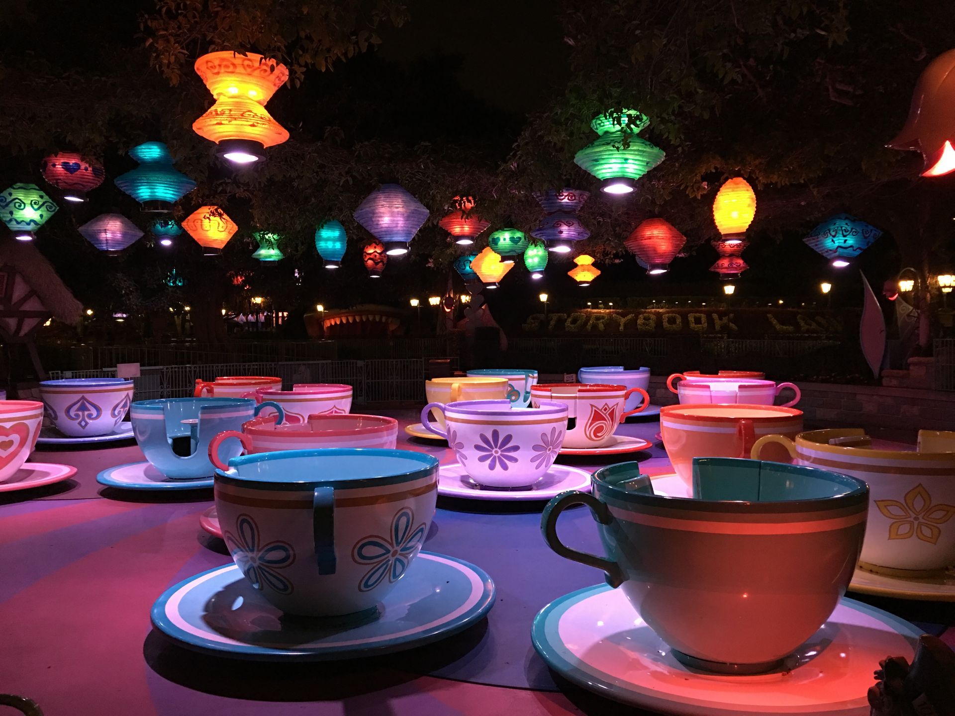 A bunch of cups and saucers on a table with lanterns in the background