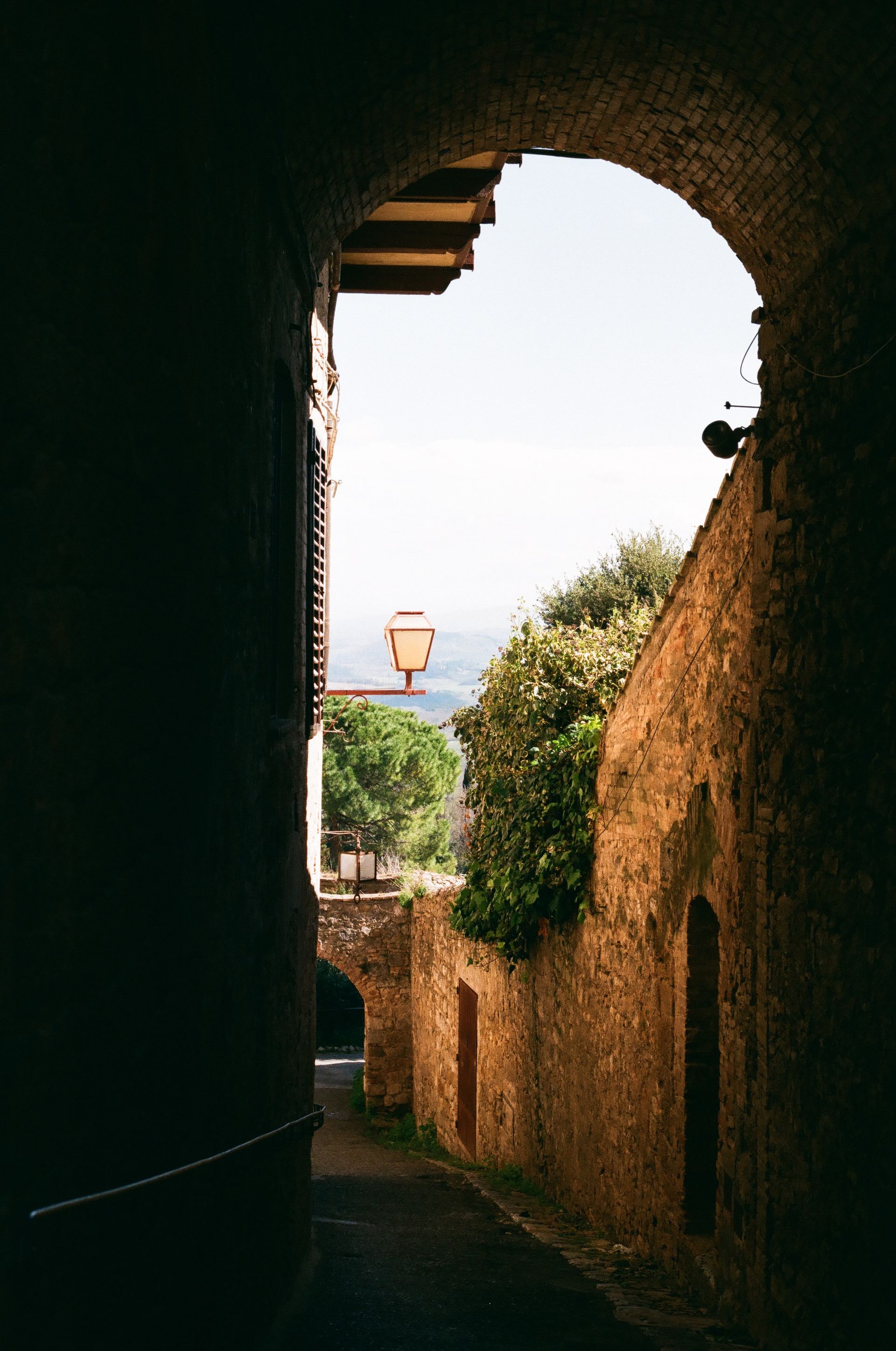 A dark alleyway with a lantern on the side of the building.